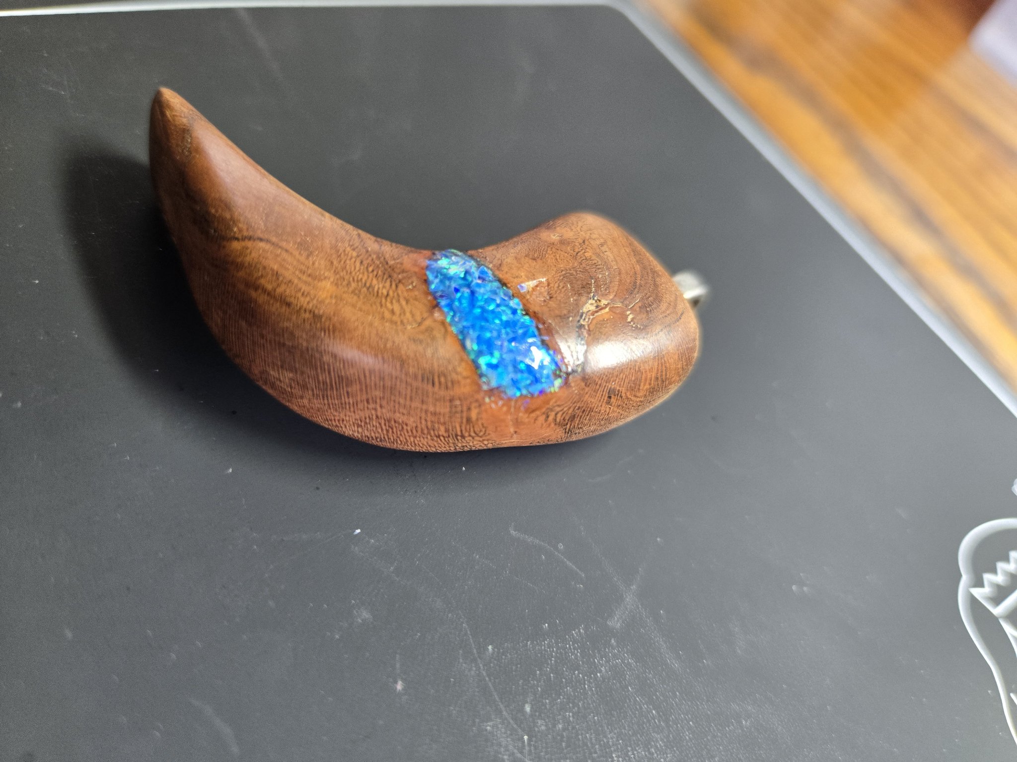 Side angle of the curved maple bear claw pendant and blue fire opal inlay
