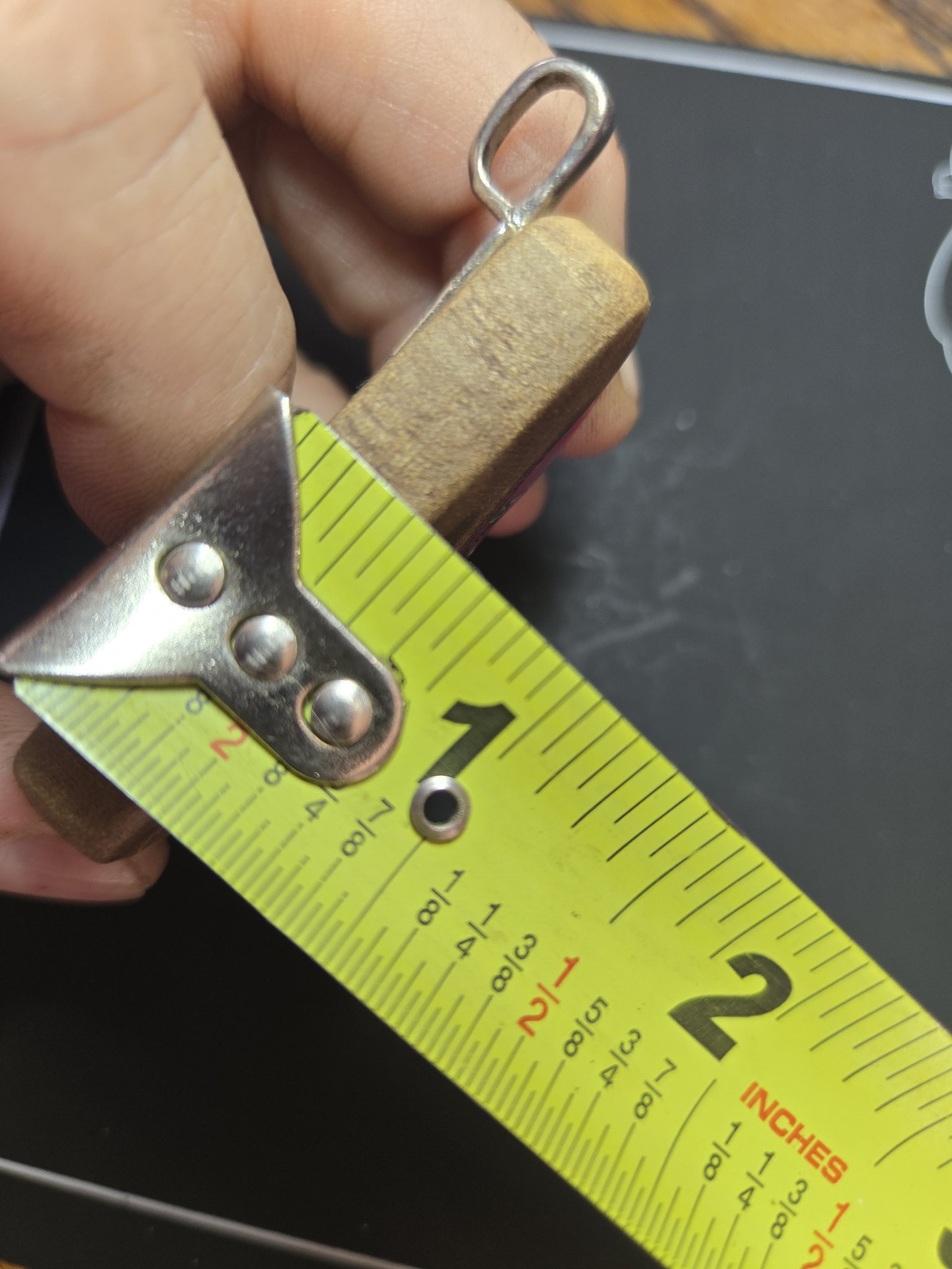 Side view of the figured maple pendant beside a tape measure showing its thickness