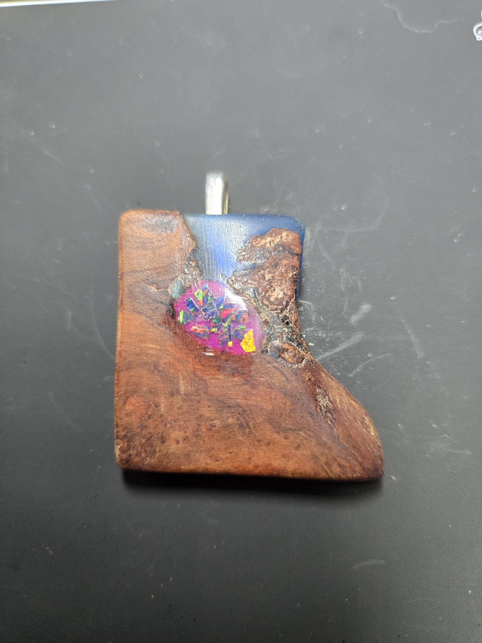 Close-up front view of a hand-finished maple pendant with blue resin and a magenta-pink crushed opal inlay