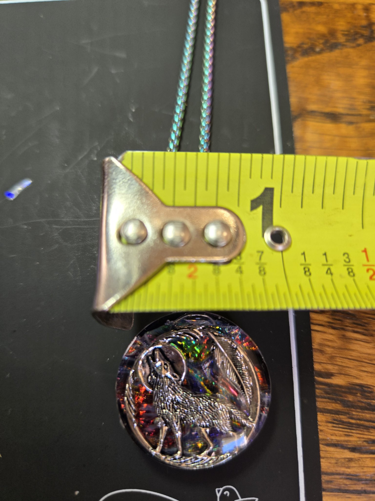 Howling wolf pendant against a tape measure showing it is about one and a half inches across