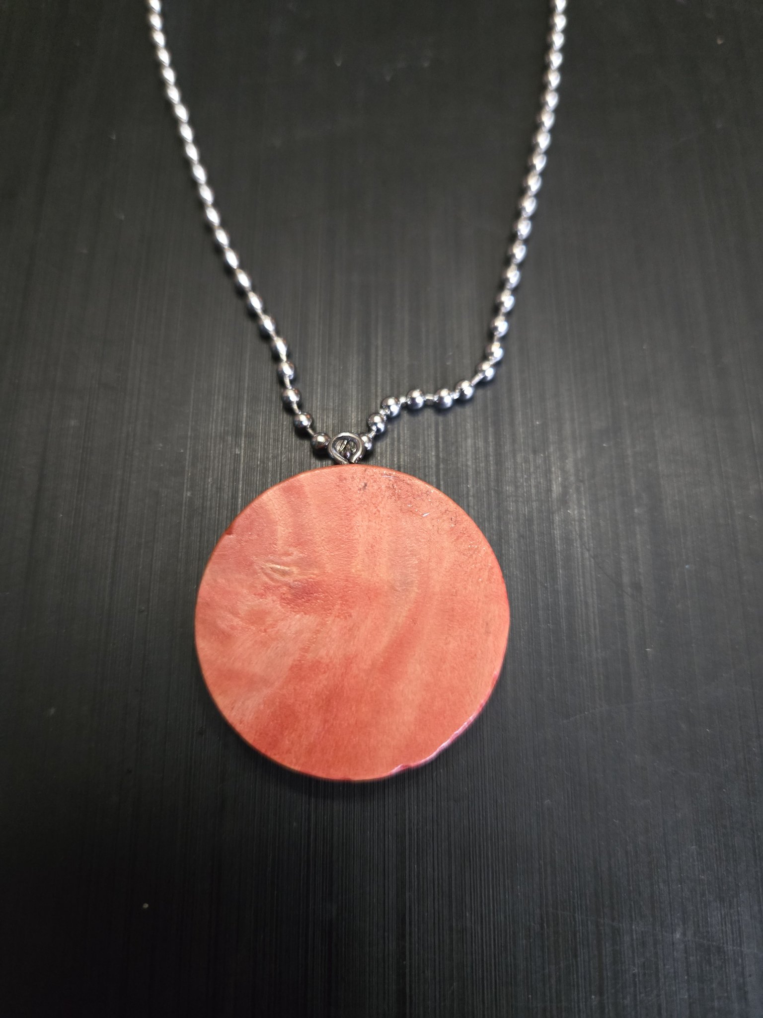 Back view of the round pendant showing its warm orange-pink natural wood grain