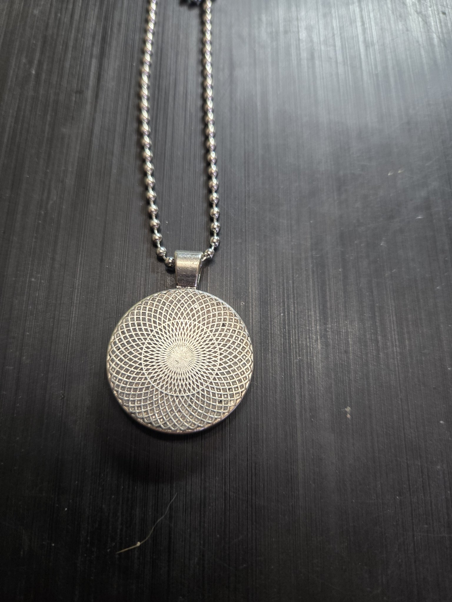 Back view of the pendant showing the silver-tone metal mandala pattern