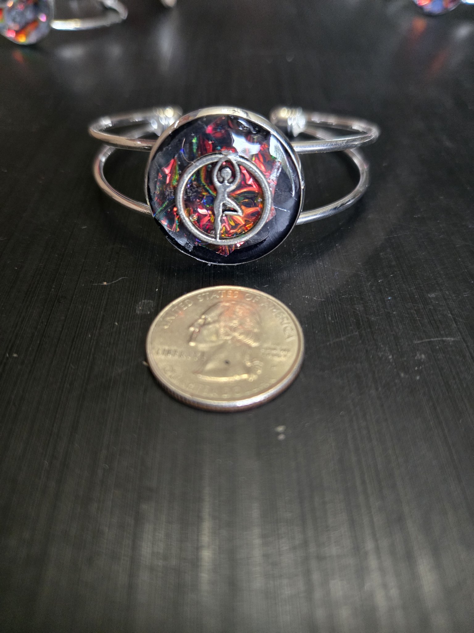 Holographic dancer cuff bracelet beside a quarter showing the medallion is approximately one and a half inches across