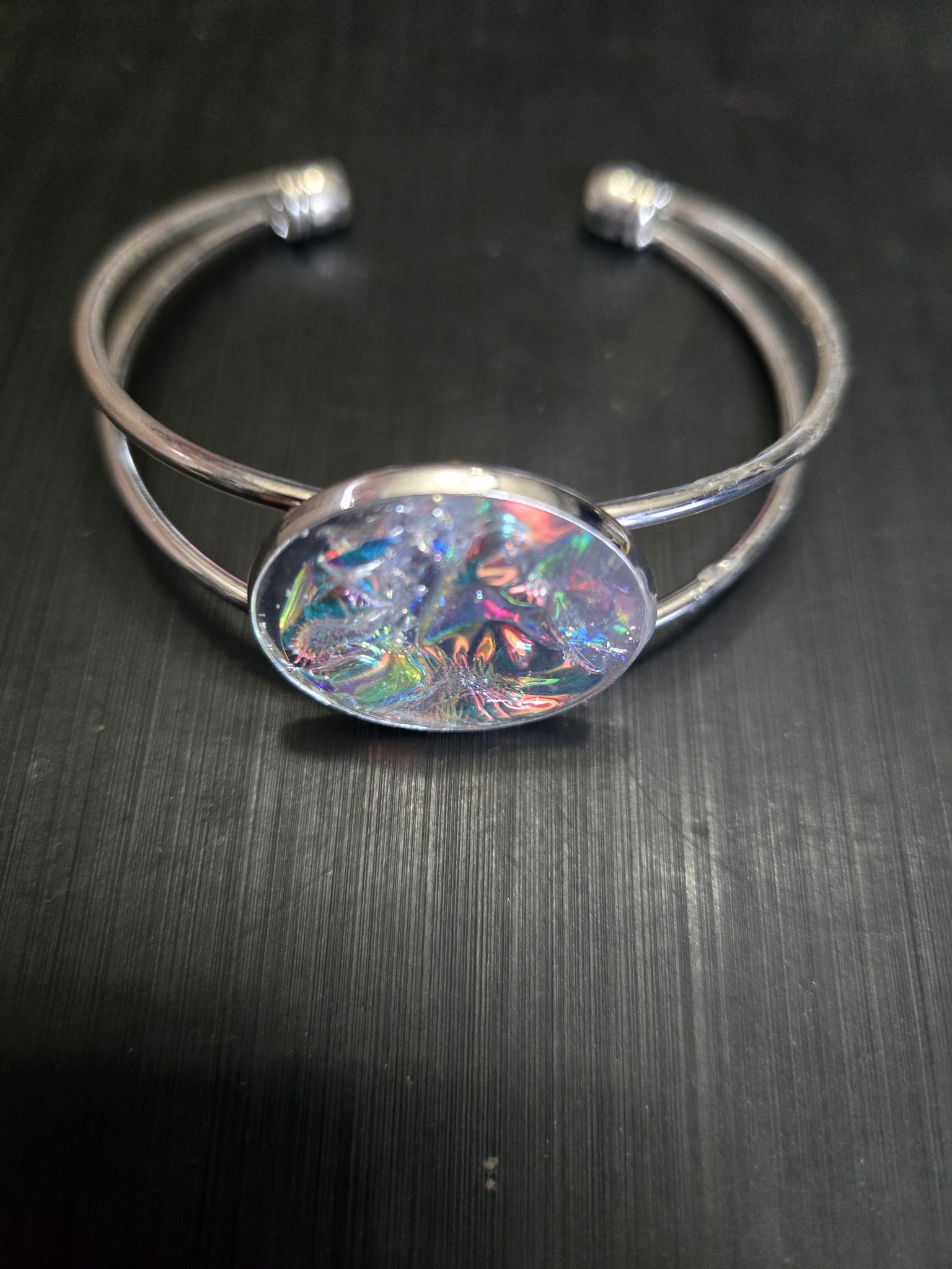 Third alternate view of the silver-tone cuff bracelet and colorful plain holographic medallion
