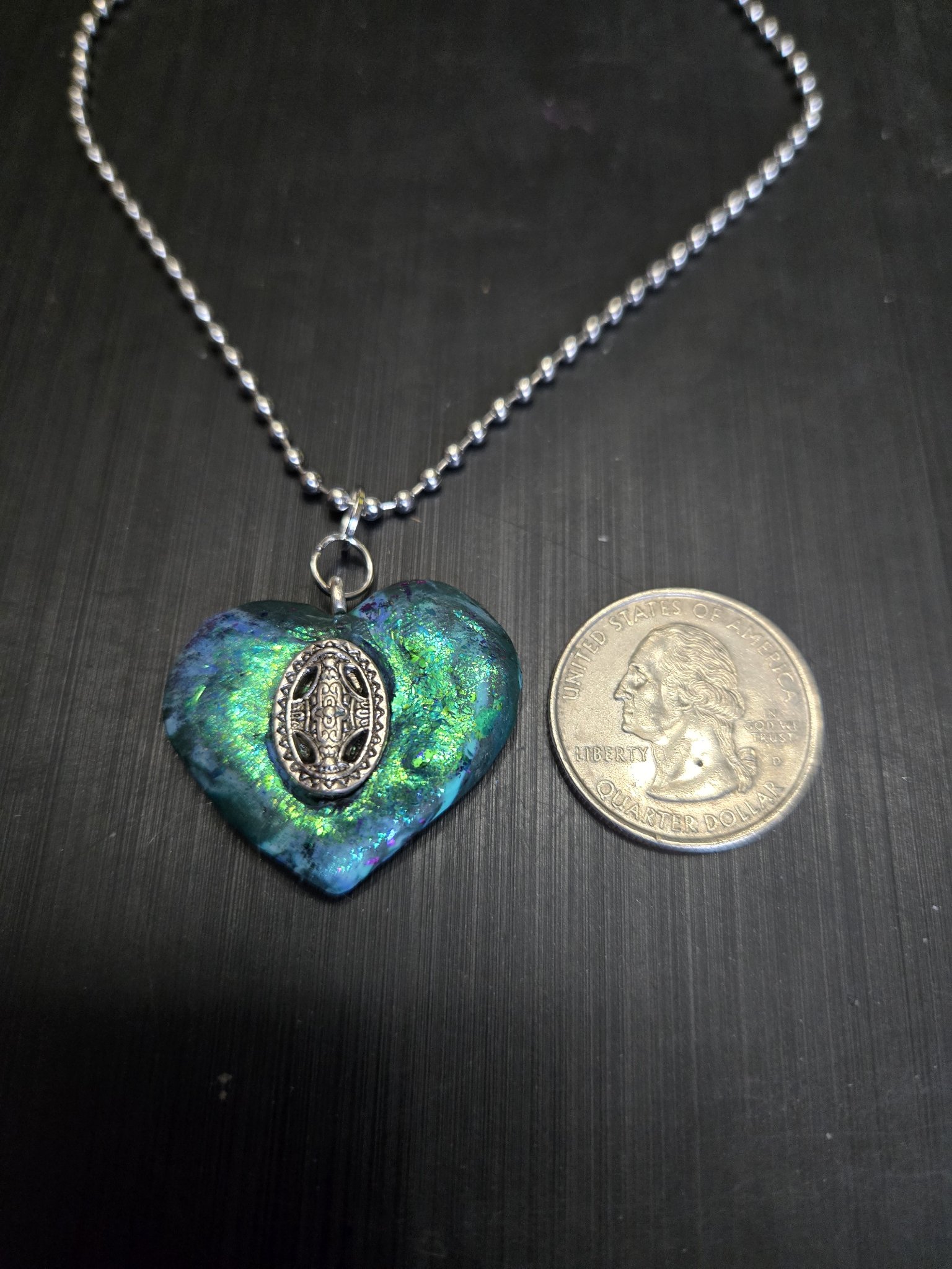 Stock 147 iridescent Celtic heart pendant beside a quarter showing it is approximately two inches across