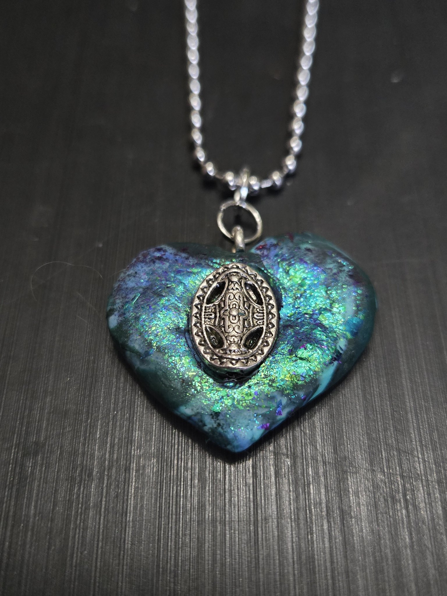 Close-up of stock 147 showing the teal, blue, and green shimmer and silver-tone Celtic-design center medallion