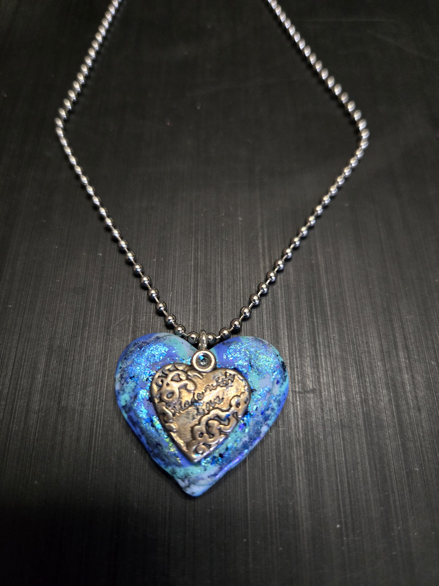 Stock 152 blue iridescent polymer clay heart pendant with a brass-tone Made with love heart charm on its ball chain