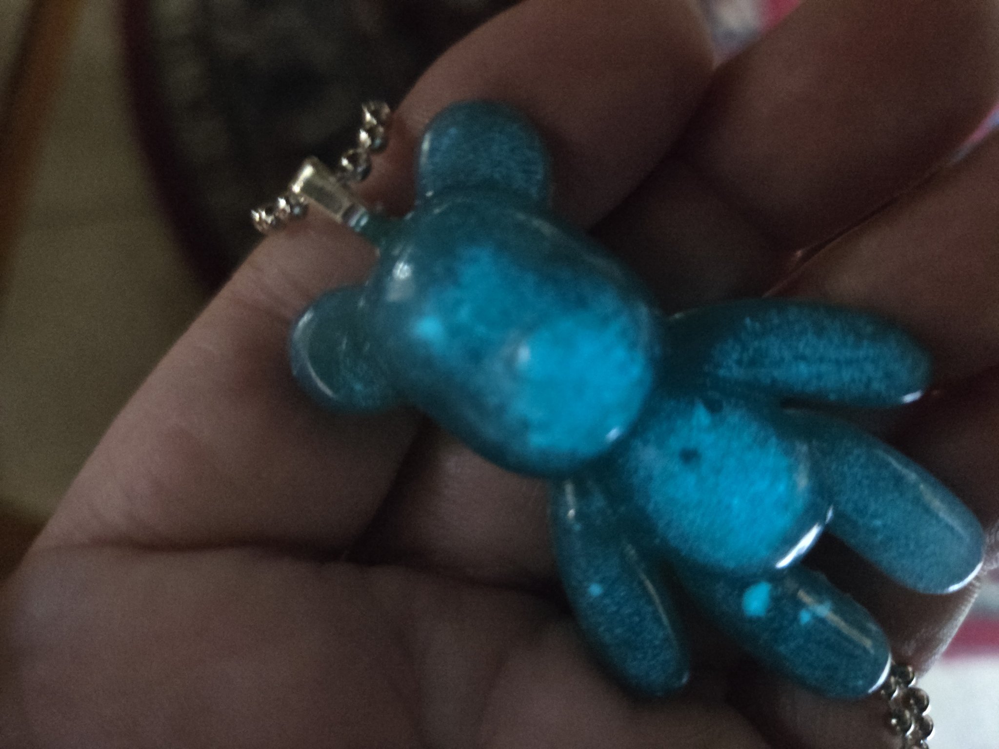 Stock 155 blue-green resin teddy bear pendant held in a hand