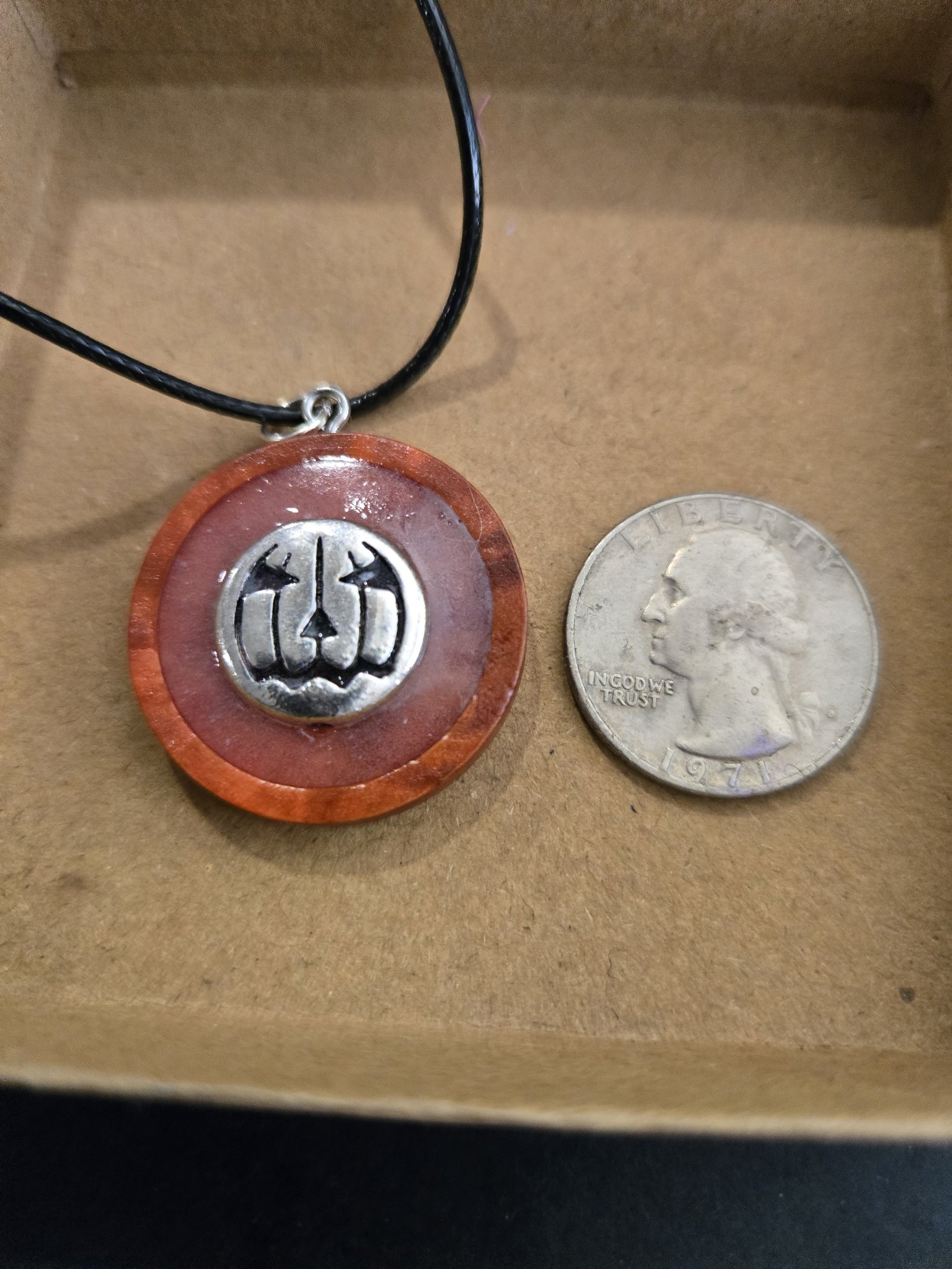 Stock 166 glow-in-the-dark pumpkin pendant beside a quarter for scale