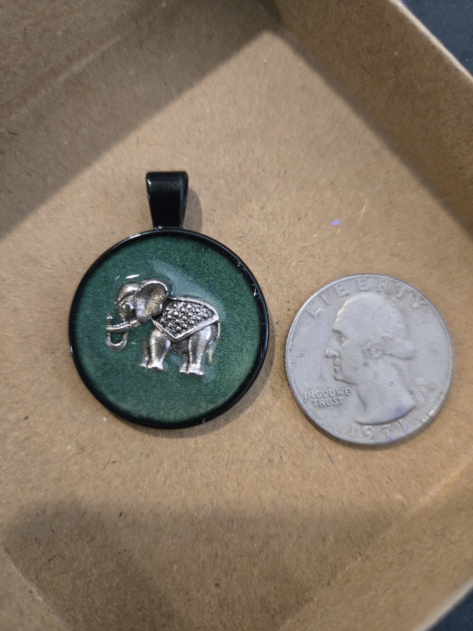 Stock 168 glow-in-the-dark elephant pendant beside a quarter for scale