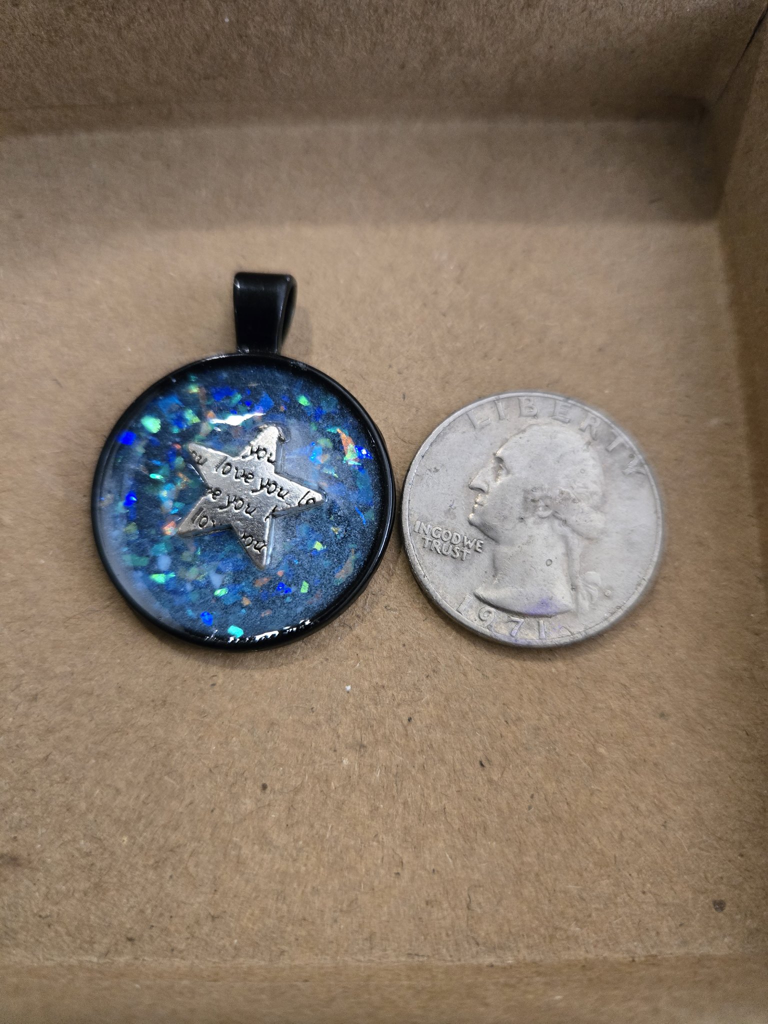 Stock 169 glow-in-the-dark love pendant beside a quarter for scale
