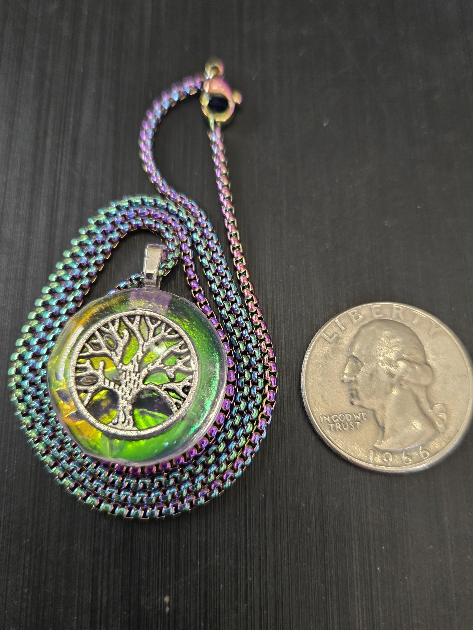 Stock 182 holographic tree of life resin pendant beside a quarter for scale