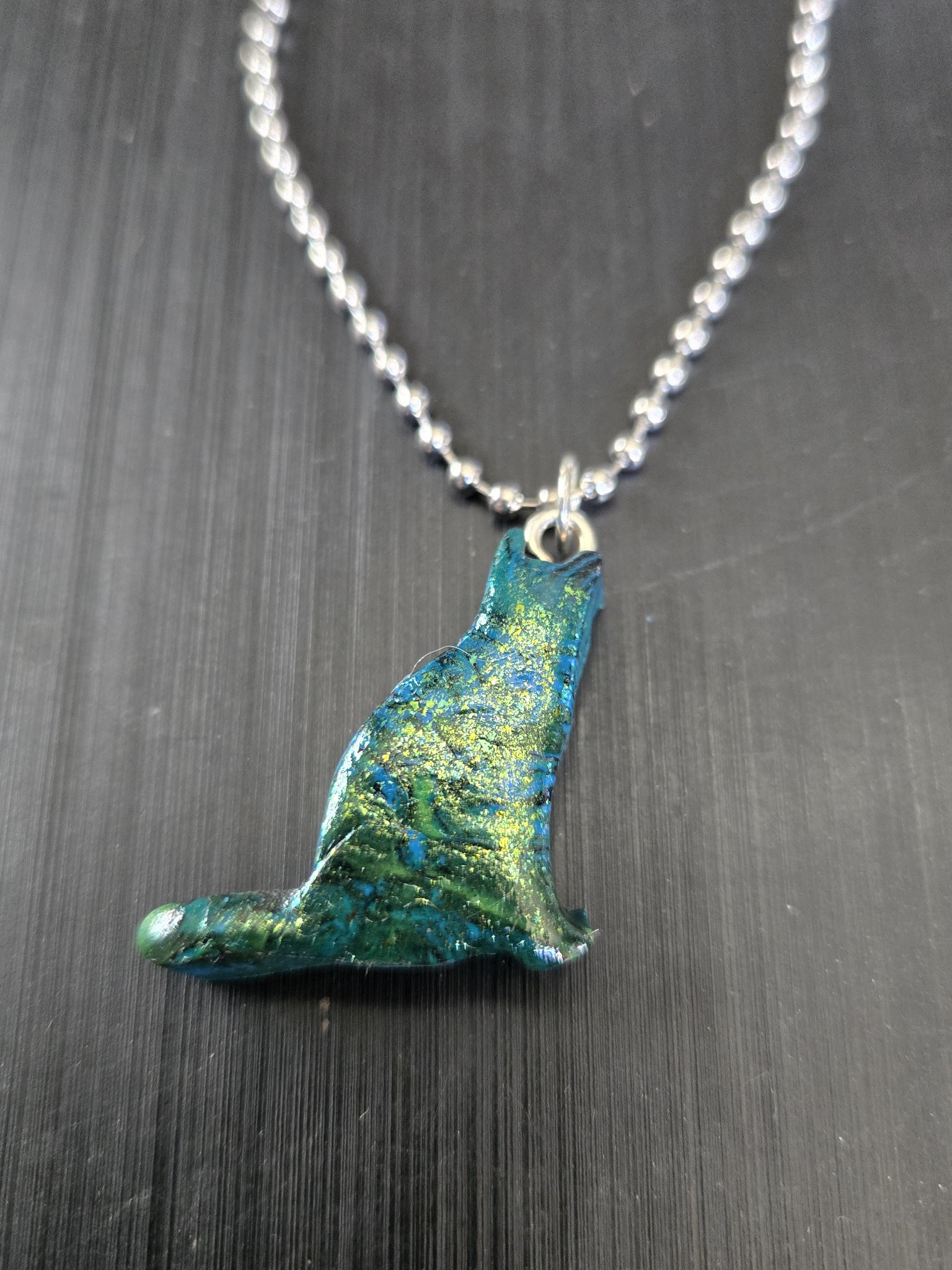 Alternate angle of stock 183 sitting cat pendant showing its blue, green, and gold mica sheen