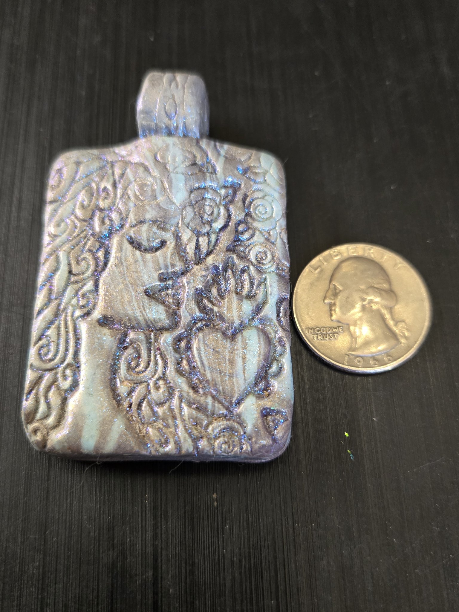 Front of stock 189 blue-pink mica face pendant beside a quarter for scale