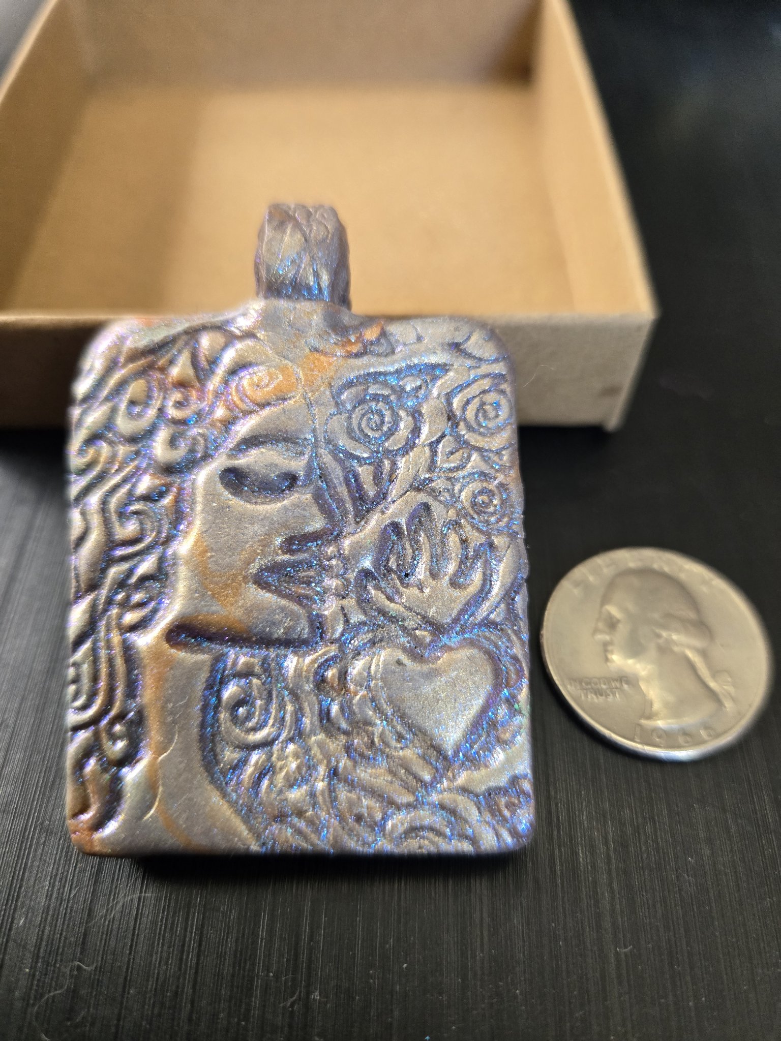 Front of stock 190 blue mica face pendant beside a quarter for scale
