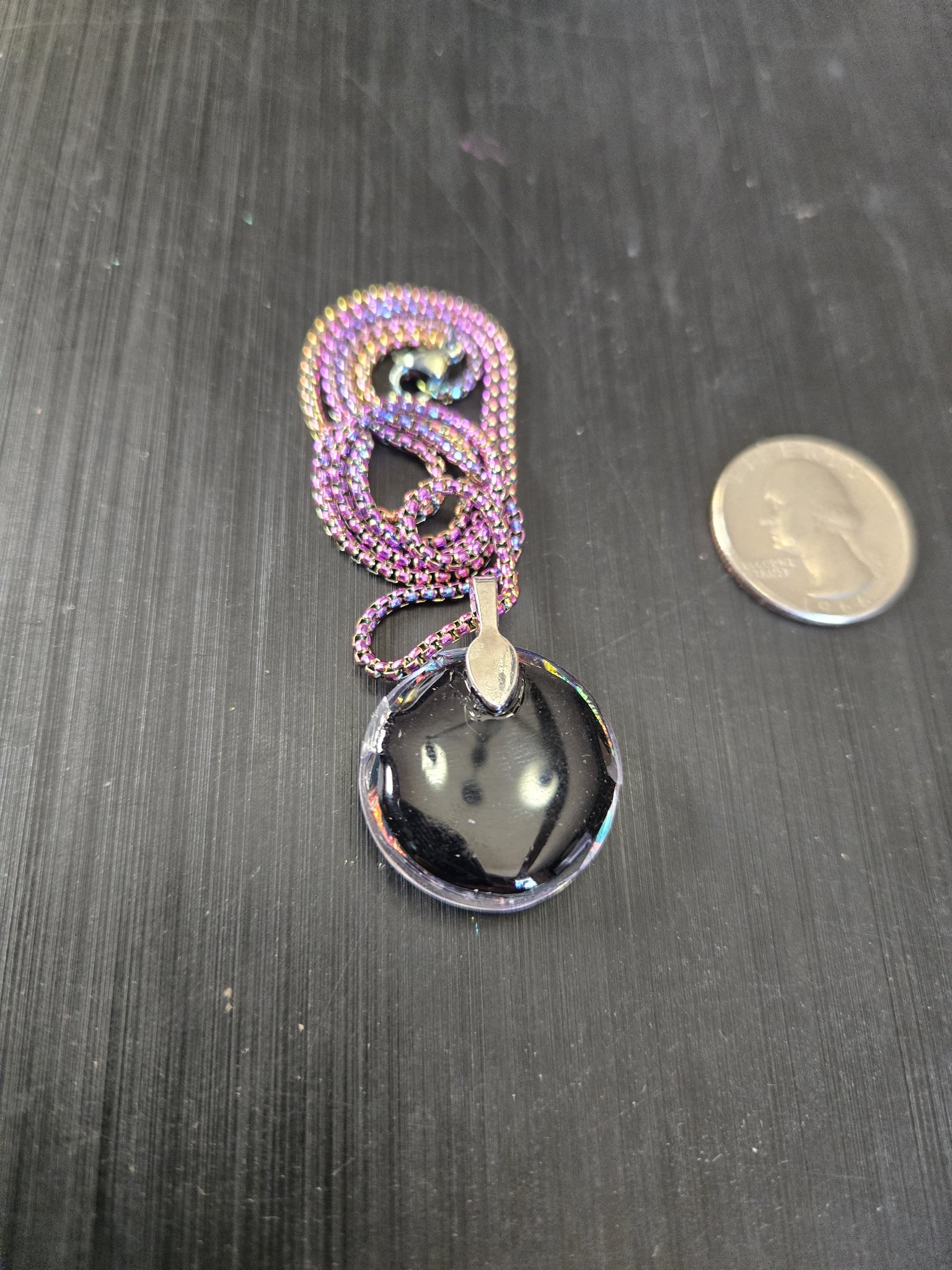 Black resin back of stock 191 holographic angel pendant beside a quarter for scale
