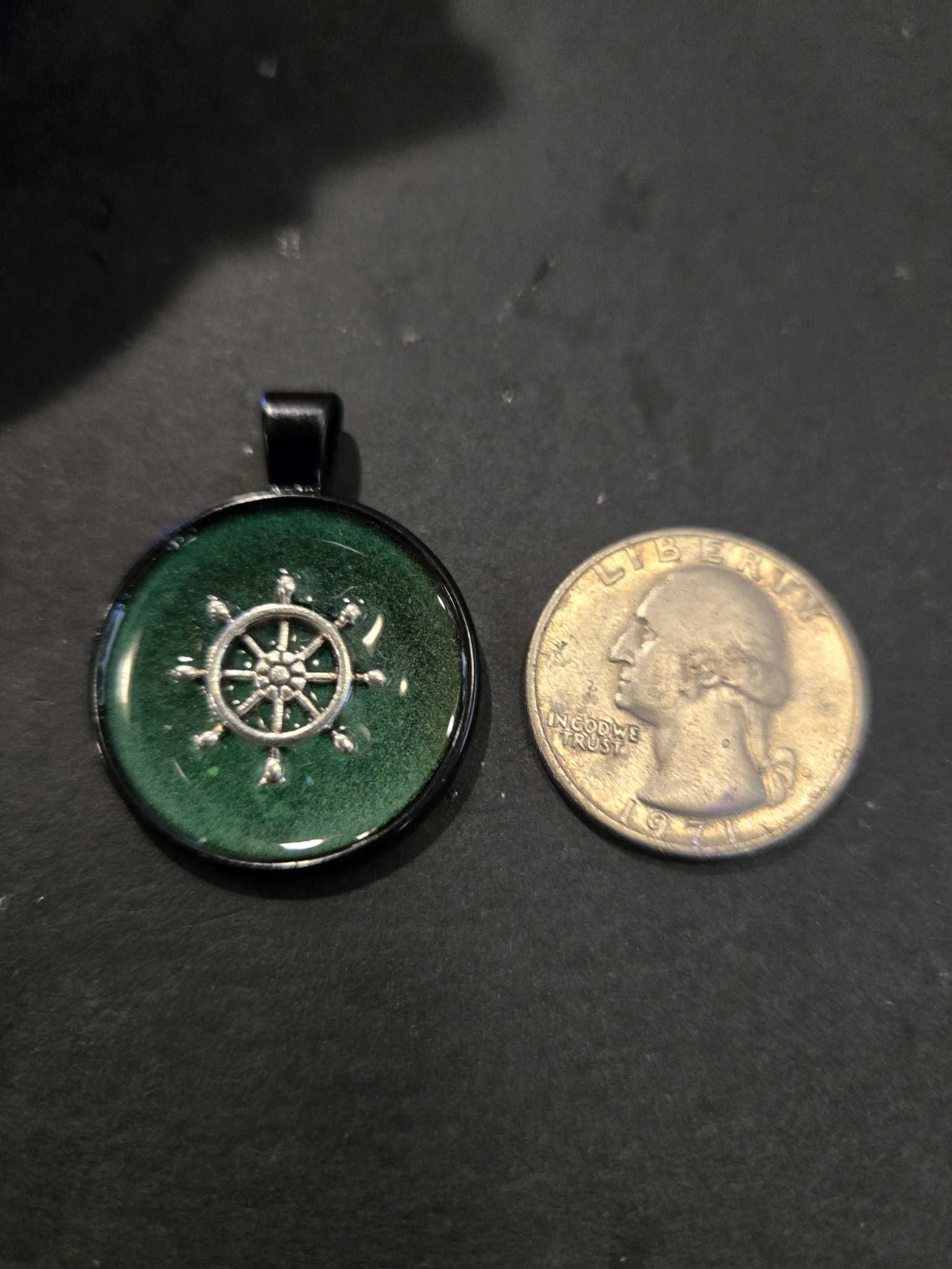 Stock 195 ship's wheel resin pendant shown beside a quarter for scale