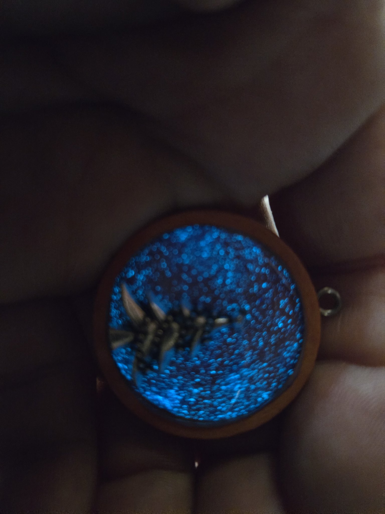 Stock 196 Christmas tree pendant glowing blue in the dark while held in a hand