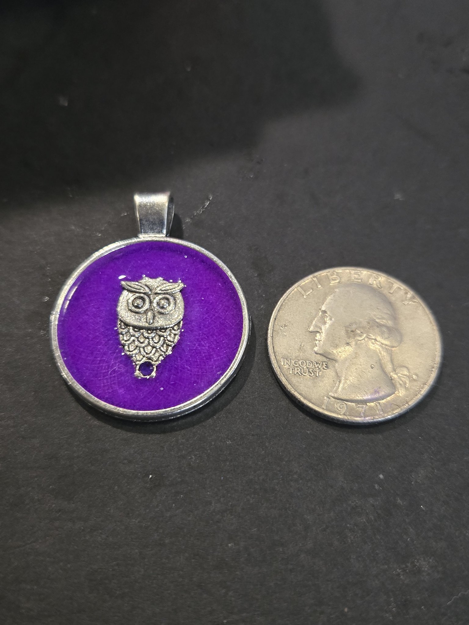 Front of stock 200 owl resin pendant beside a quarter for scale