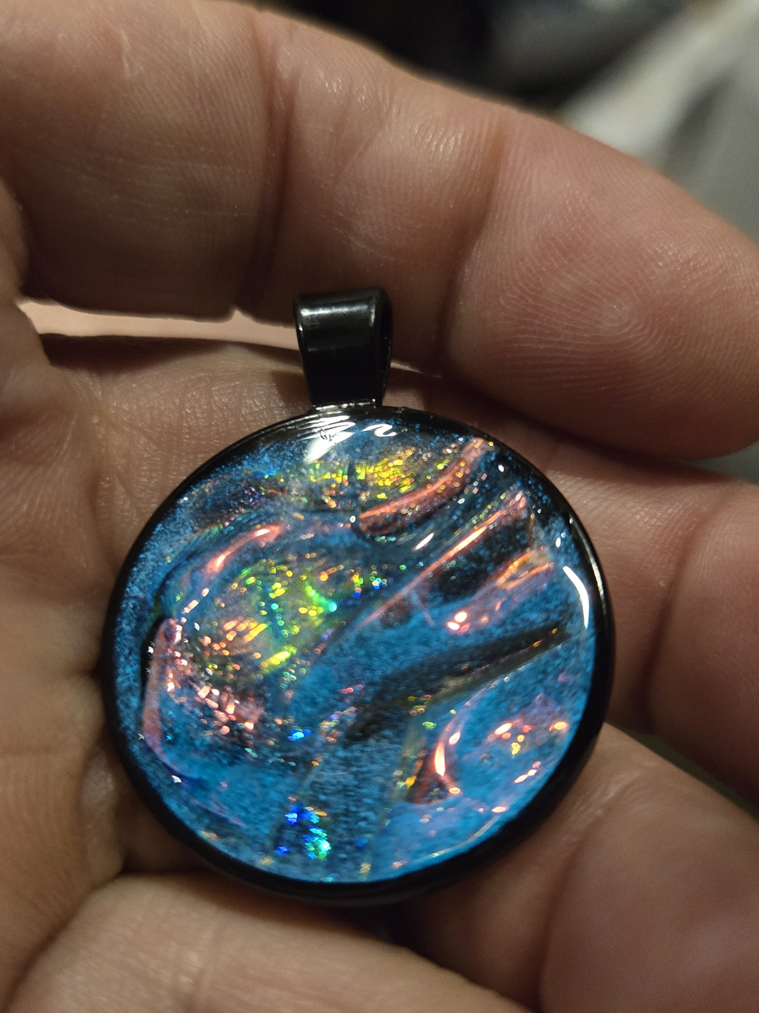 Stock 204 blue holographic resin pendant shown from the front in a hand