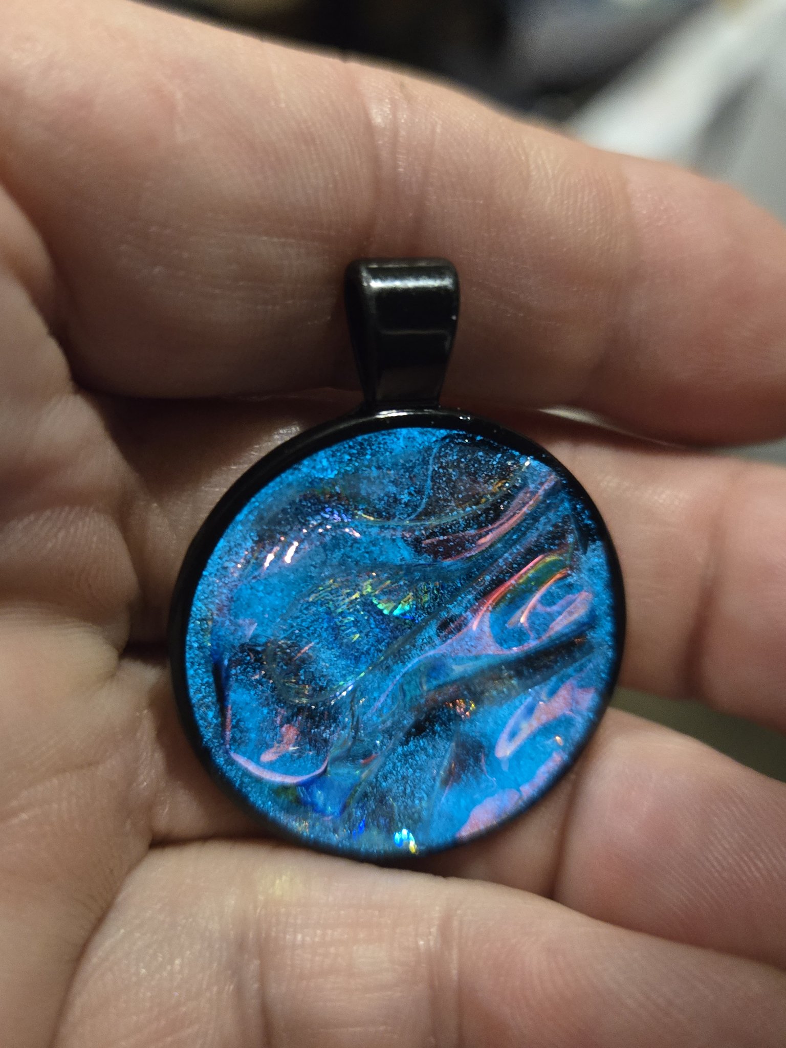 Second alternate in-hand front view of stock 204 blue holographic resin pendant