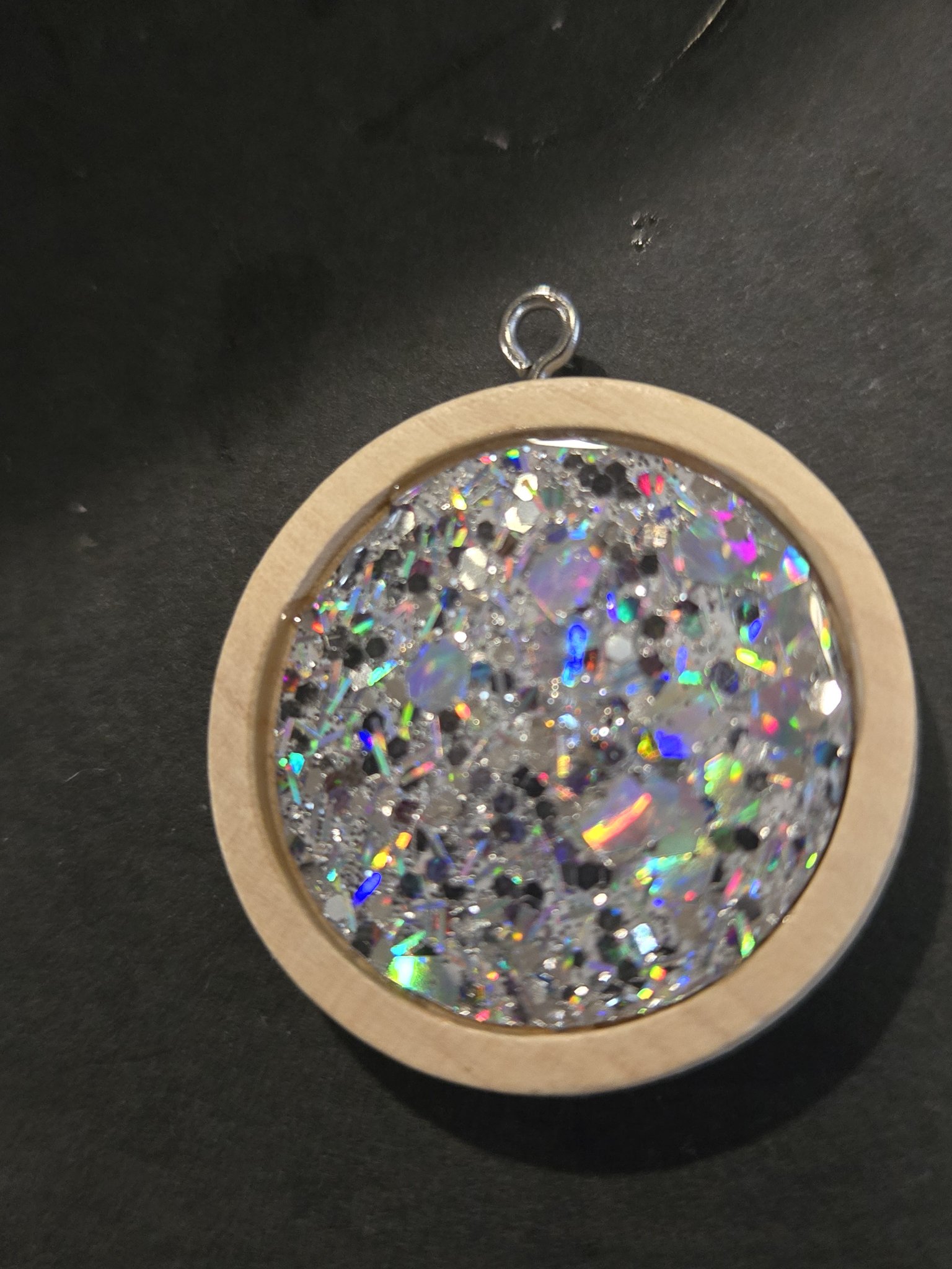 Stock 205 round holographic iridescent resin pendant set in a wood frame, shown from the front