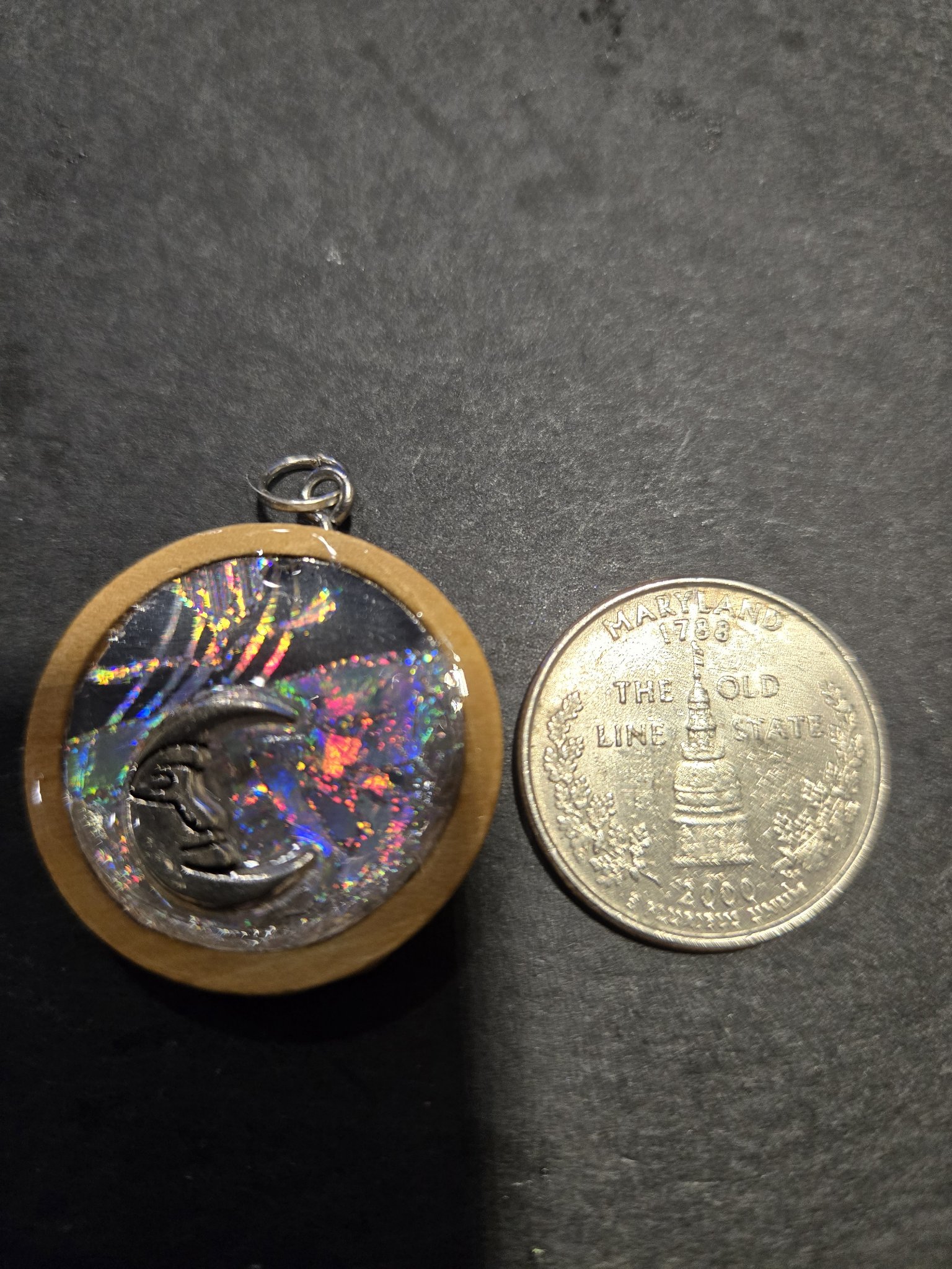 Front of stock 209 holographic moon pendant beside a quarter for scale