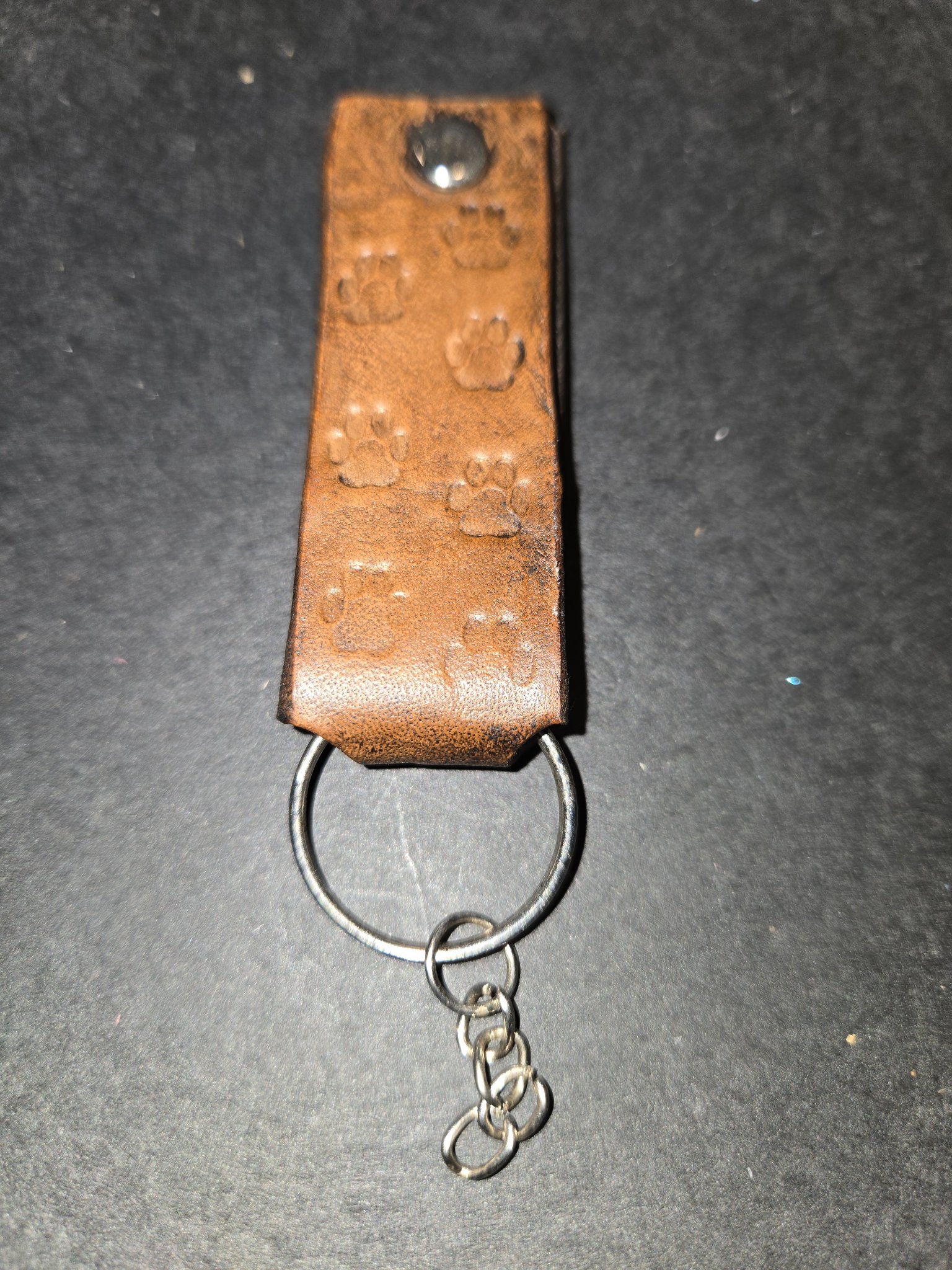 Stock 237 brown leather keychain hand-stamped with dog paw prints, shown with its silver-tone rivet, split key ring, and short chain