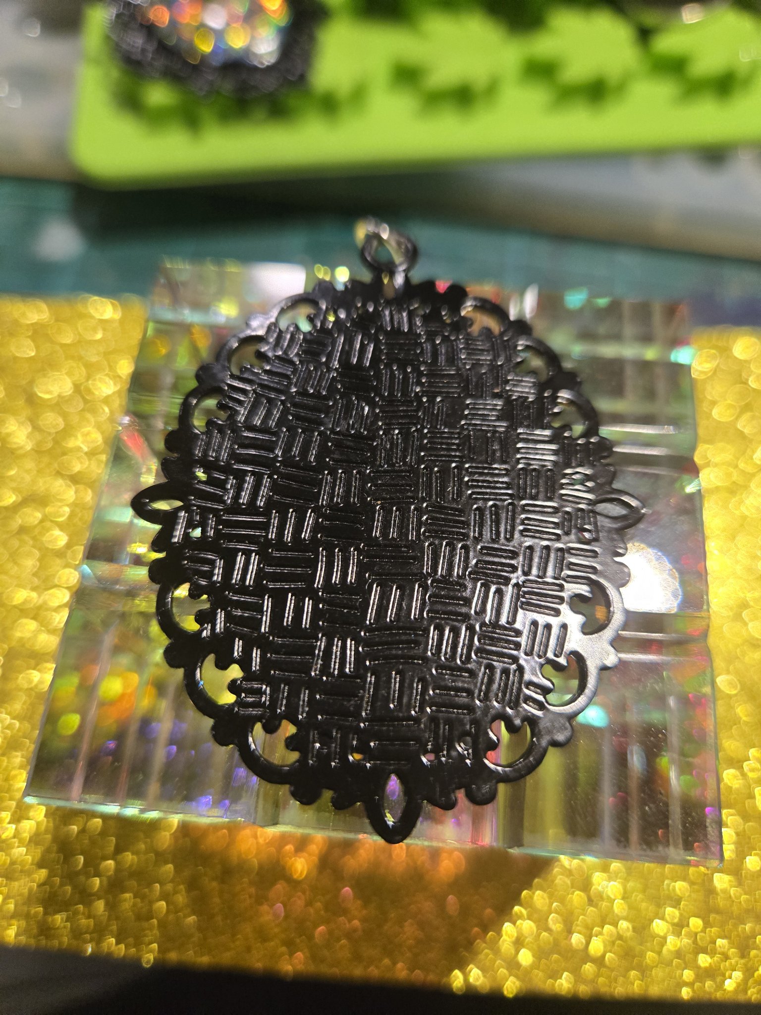 Back of stock 253 holographic filigree pendant, showing the black woven-texture metal back of the filigree frame