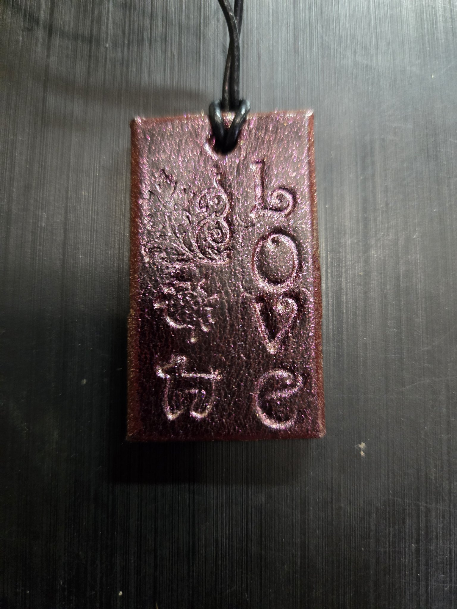 Alternate front angle of the pink metallic leather pendant showing the hand-stamped LOVE lettering and flowers