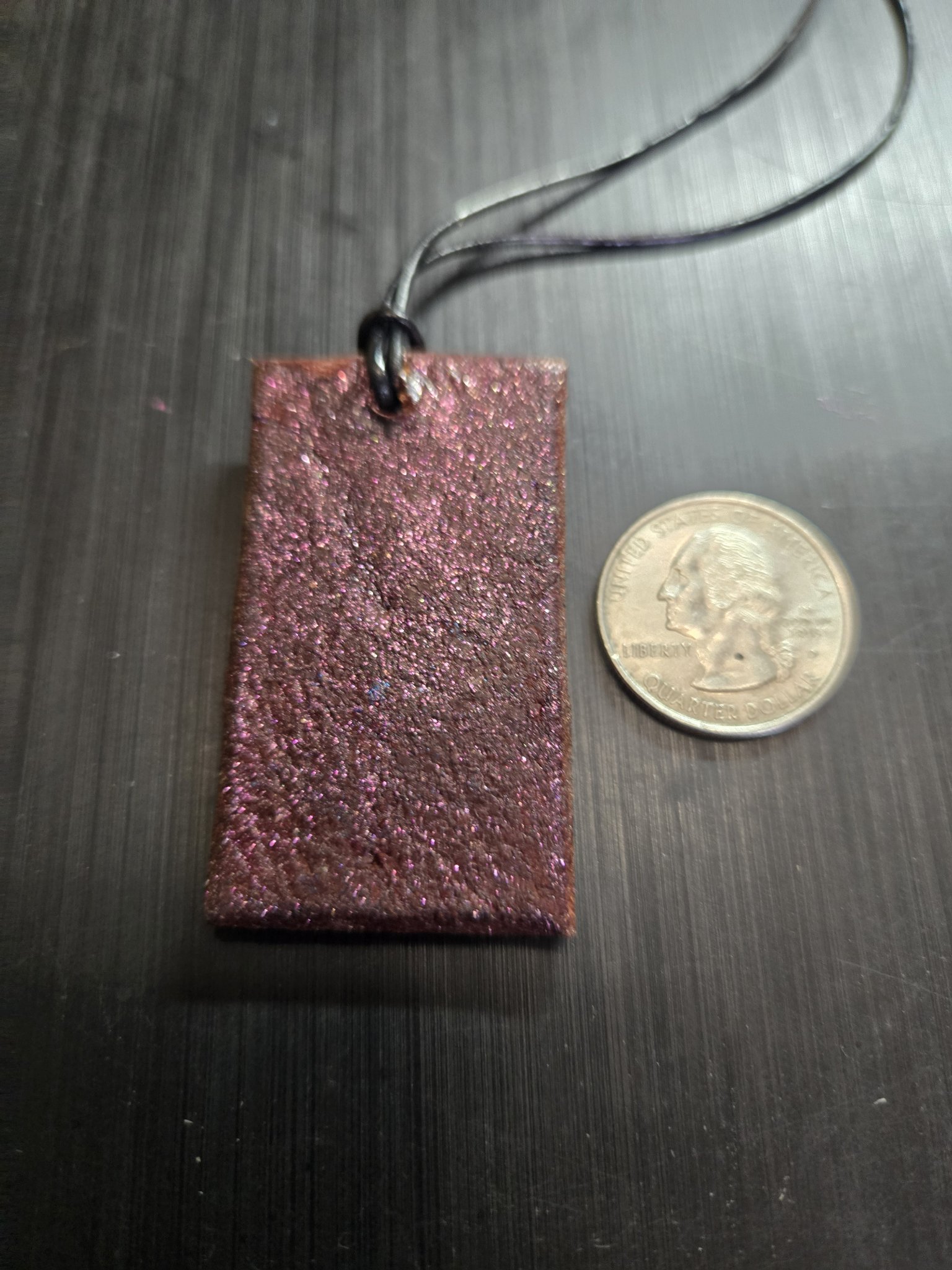 Sparkling pink back of the leather LOVE pendant beside a quarter