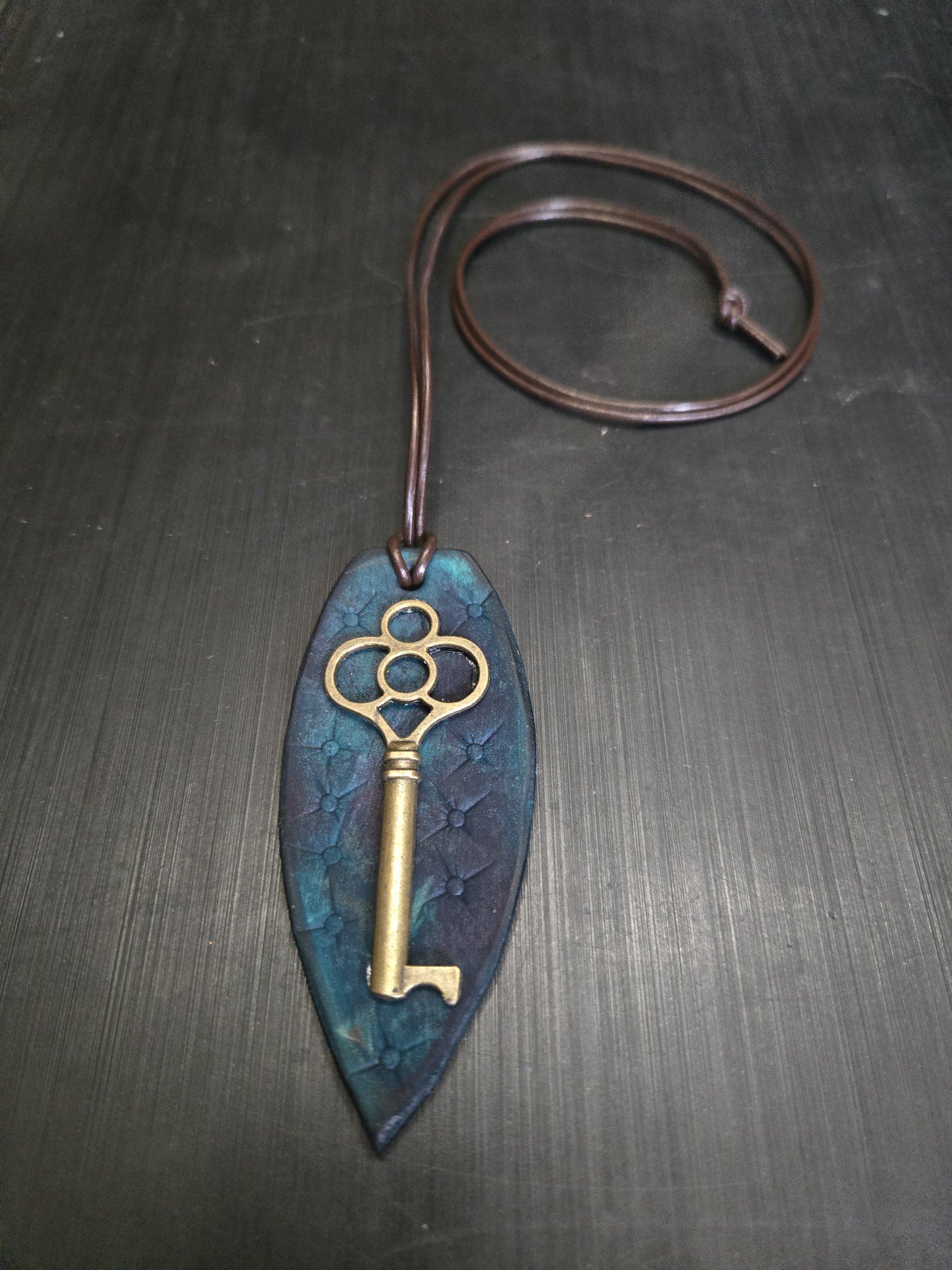 Stock 144 teal quilted-pattern leather pendant with brass key charm on a long brown leather cord