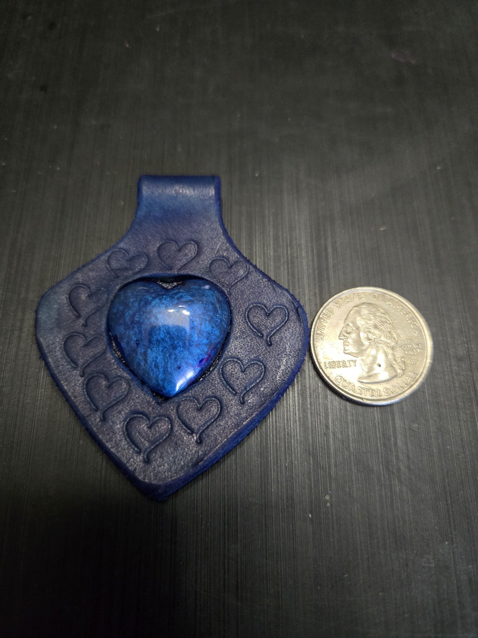 Front of stock 149 blue leather heart pendant beside a quarter showing it is approximately three inches long