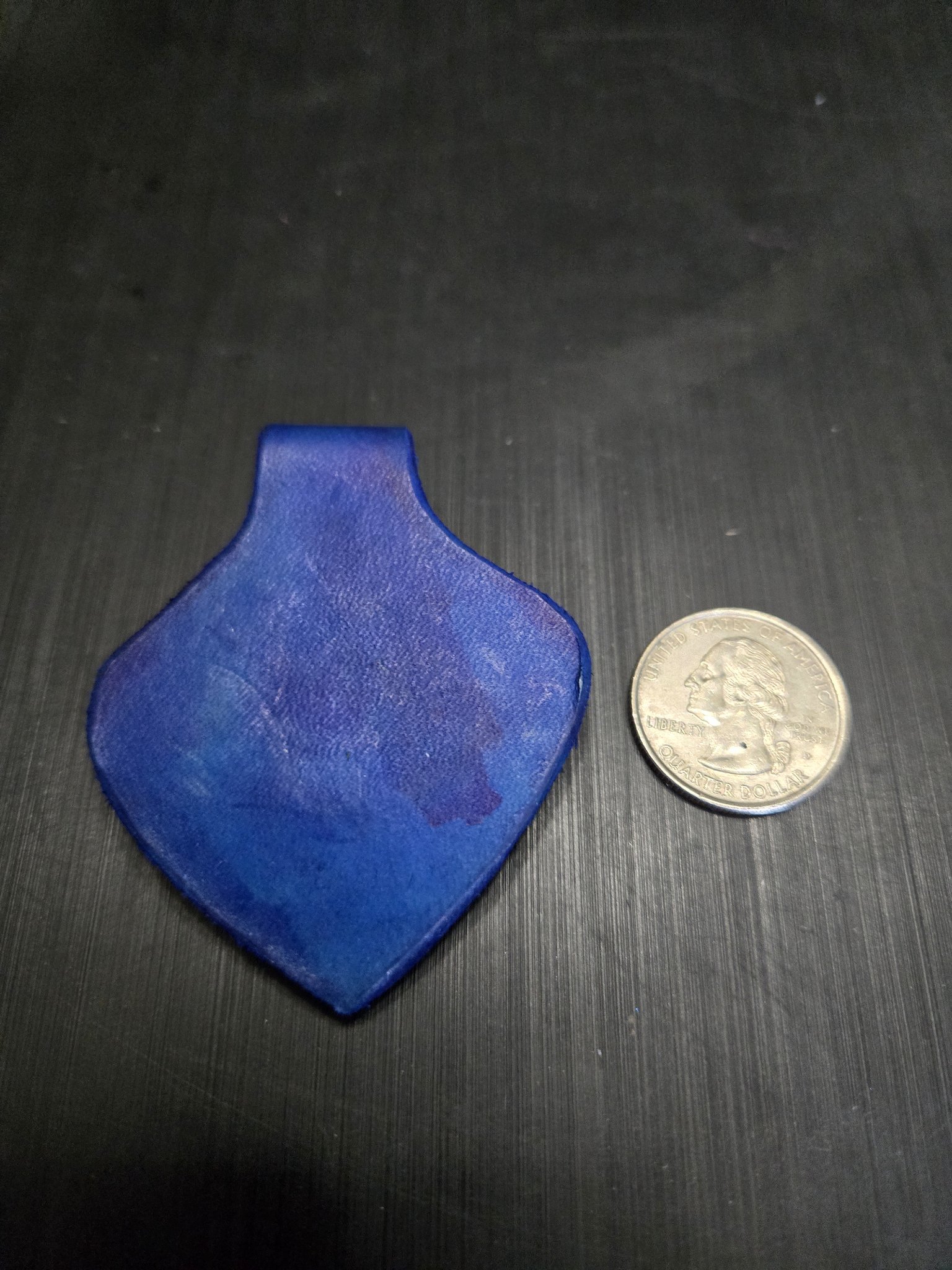 Back of stock 149 blue leather heart pendant beside a quarter for scale
