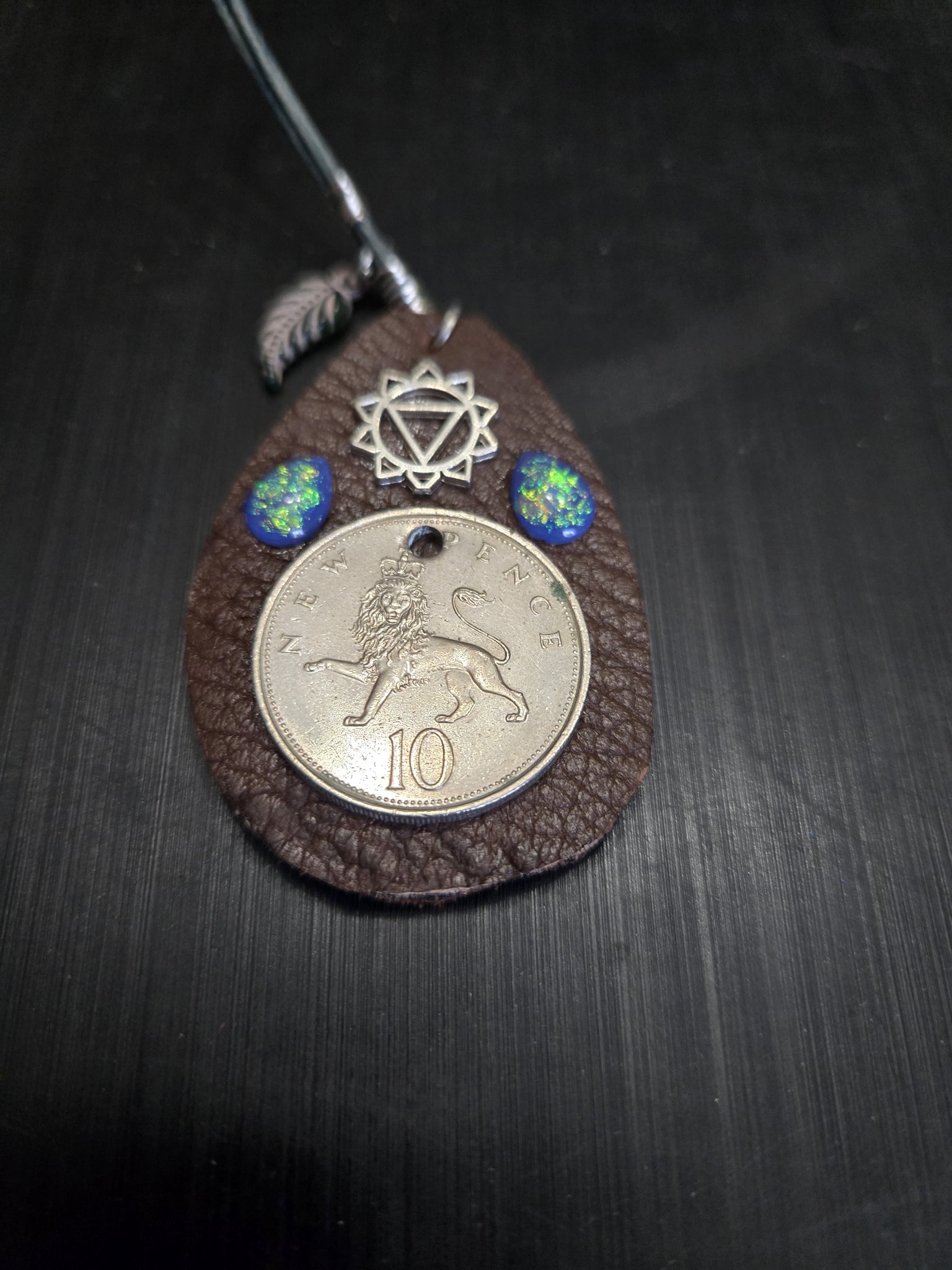 Stock 150 brown buffalo hide leather pendant with a British 10 new pence lion coin, silver-tone chakra charm, two blue fire opal teardrops, and a feather charm