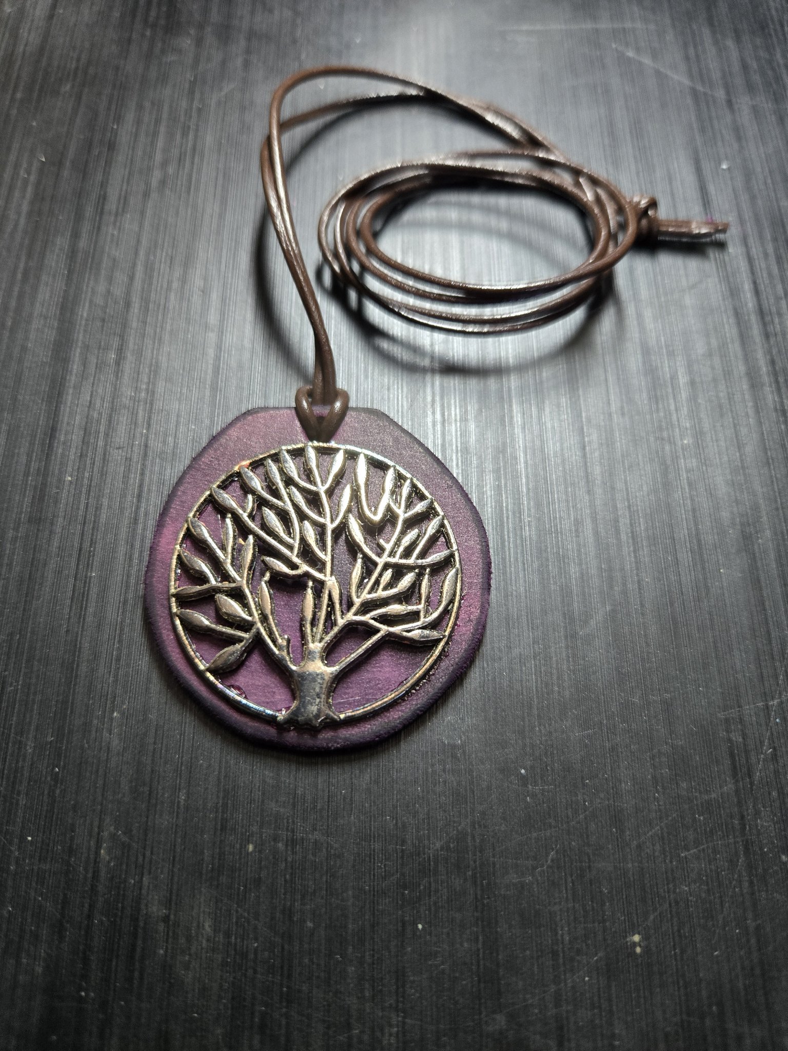 Stock 154 dark purple round leather pendant with a silver-tone Tree of Life medallion on its brown leather cord