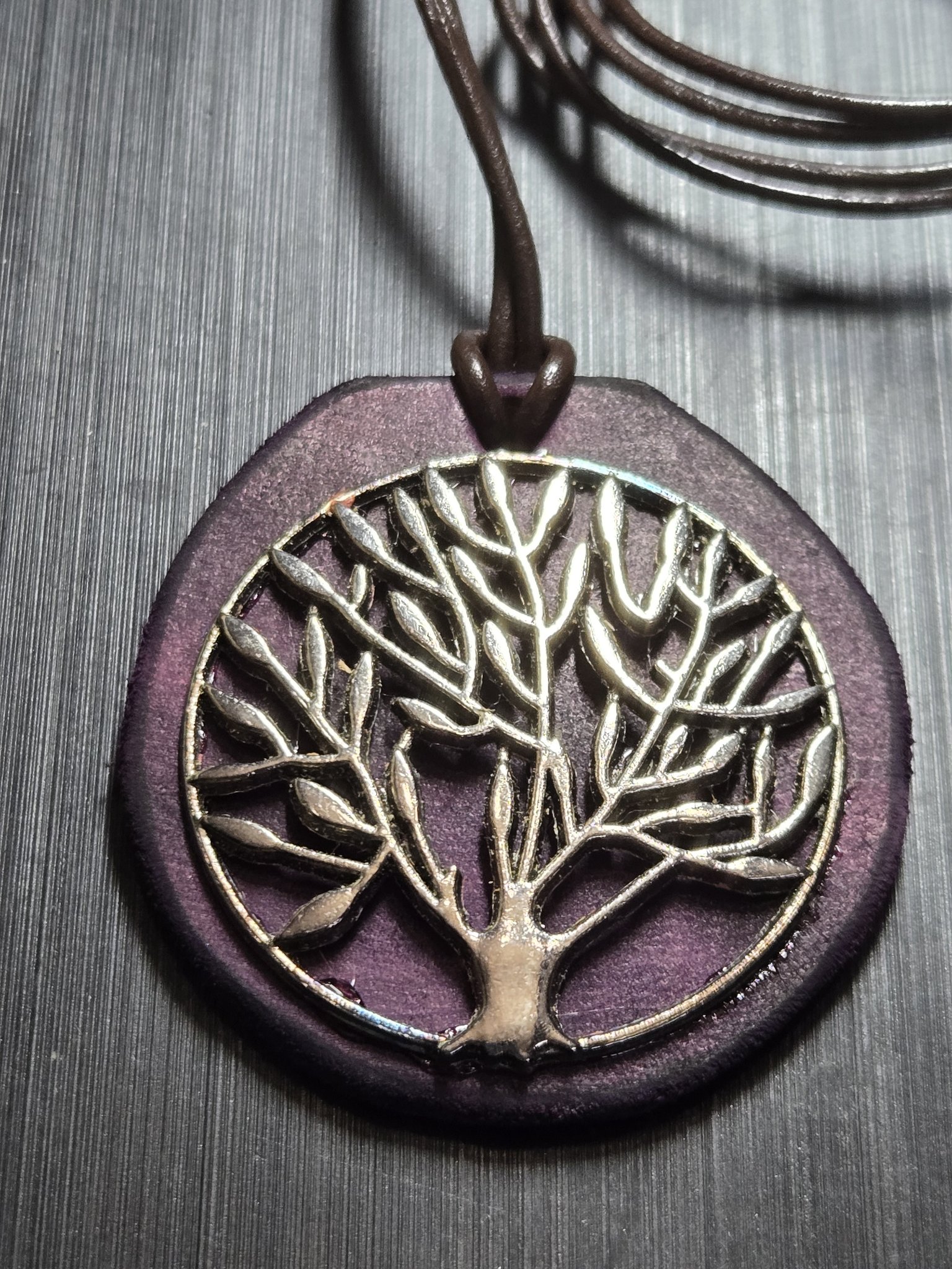 Close-up of stock 154 showing the silver-tone Tree of Life medallion on dark purple leather