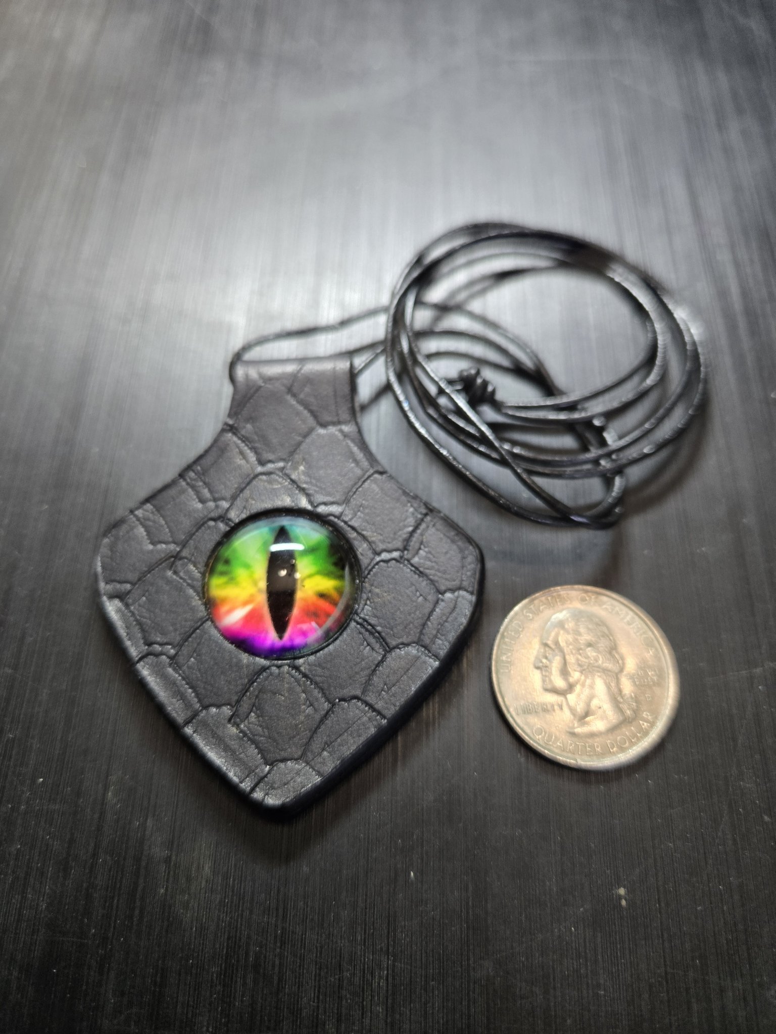 Stock 156 rainbow dragon eye leather pendant beside a quarter for scale
