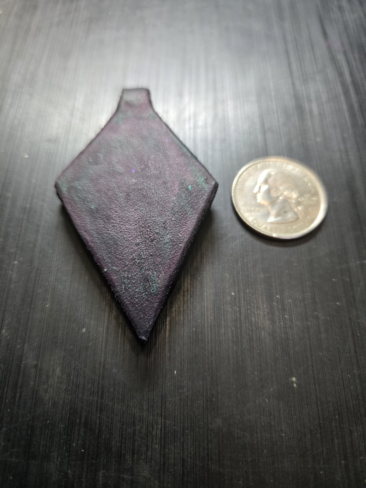Back of stock 157 black leather pendant beside a quarter for scale
