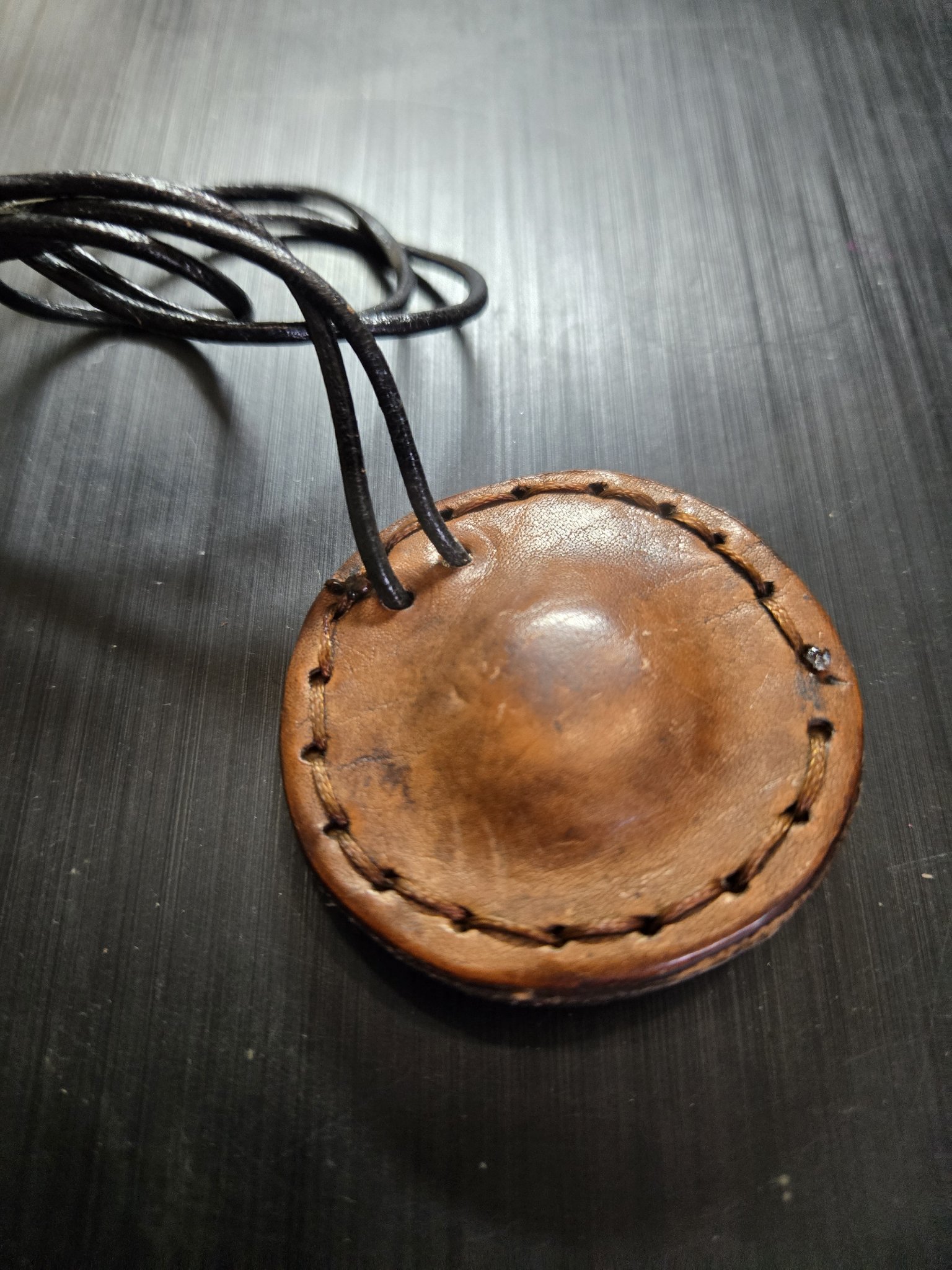 Back of stock 160 showing the hand-sewn brown leather pendant and 26-inch black leather necklace