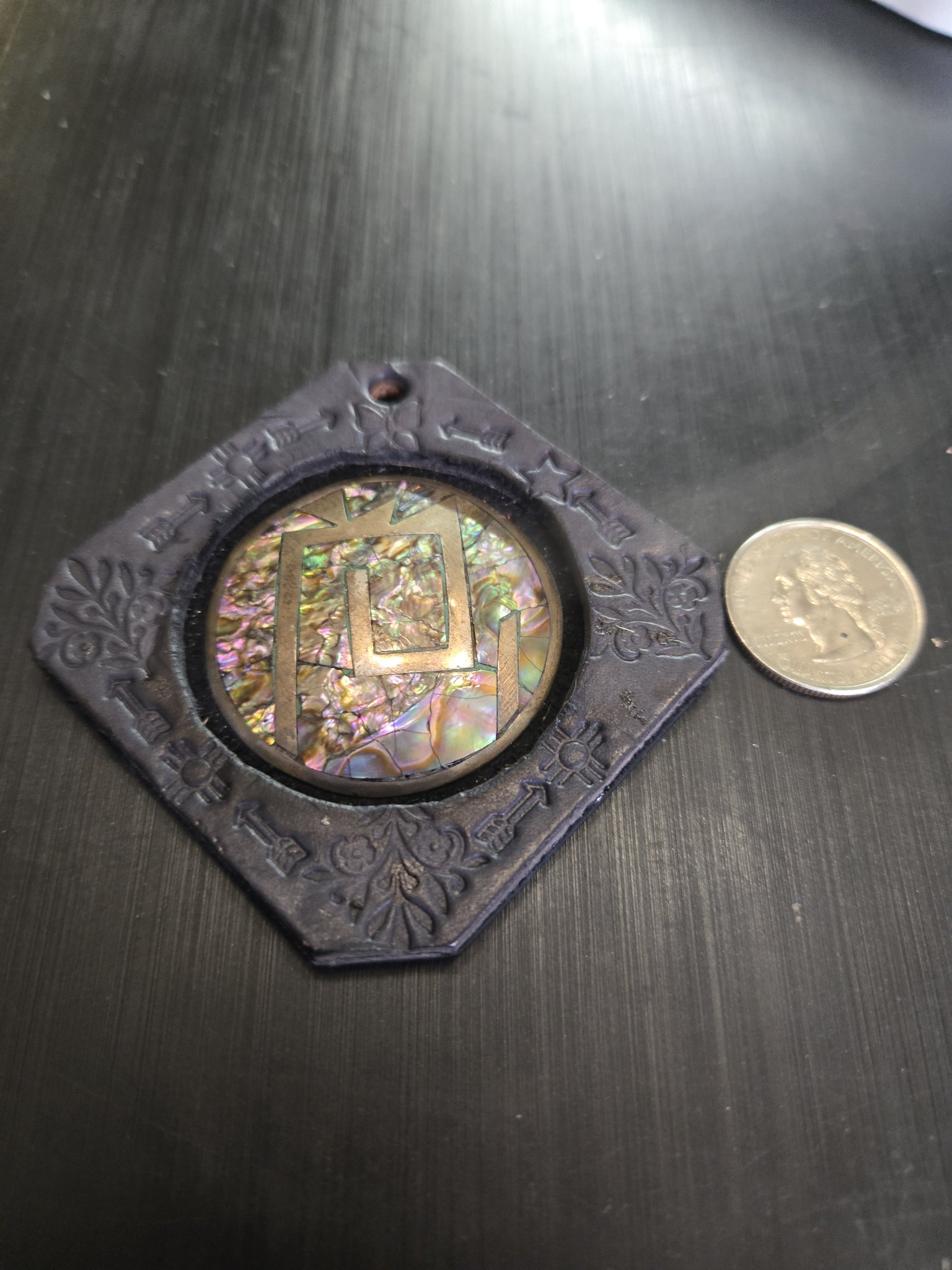 Stock 162 black leather abalone and sterling silver pendant beside a quarter for scale