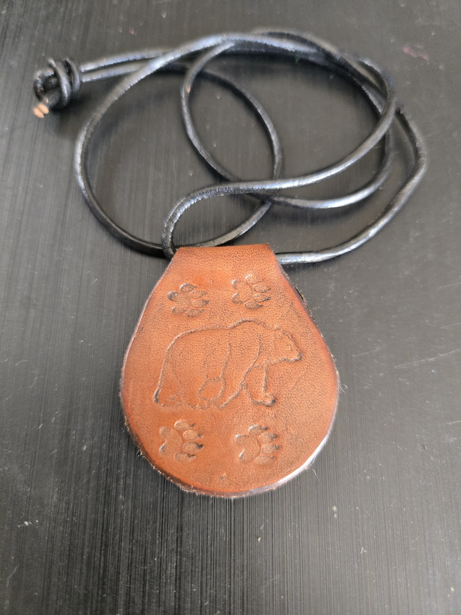 Stock 176 brown leather pendant hand-stamped with a grizzly bear and paw prints, shown in a front close-up