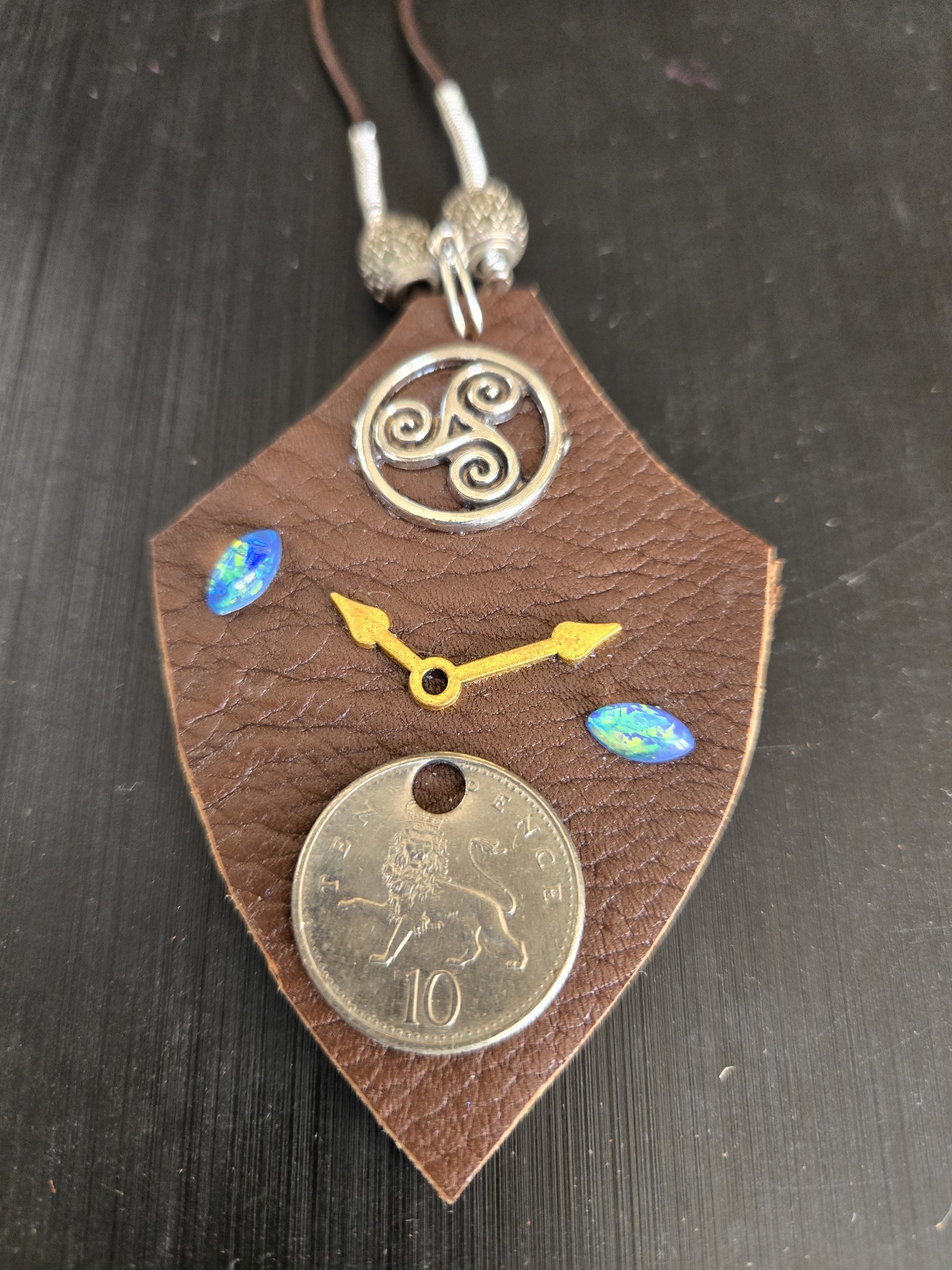 Alternate angle of stock 178 showing its brown buffalo leather shield, trinity medallion, clock hands, 10 pence coin, and holographic cabochons
