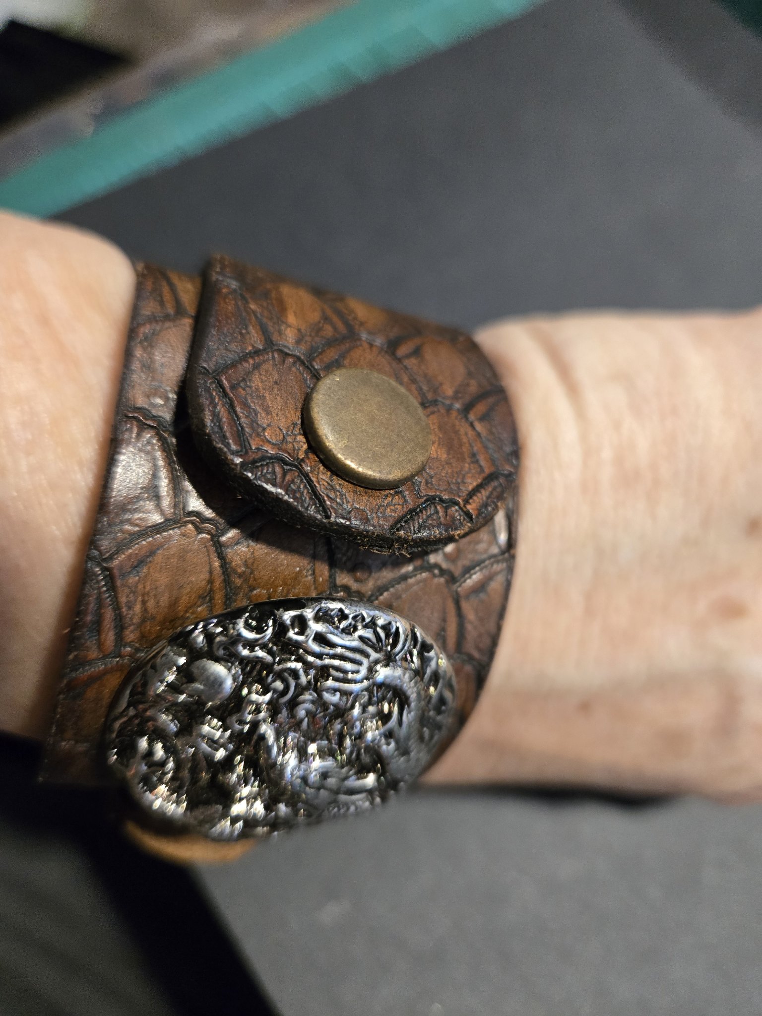 Side view of stock 214 showing the bronze snap and raised silver-tone dragon emblem