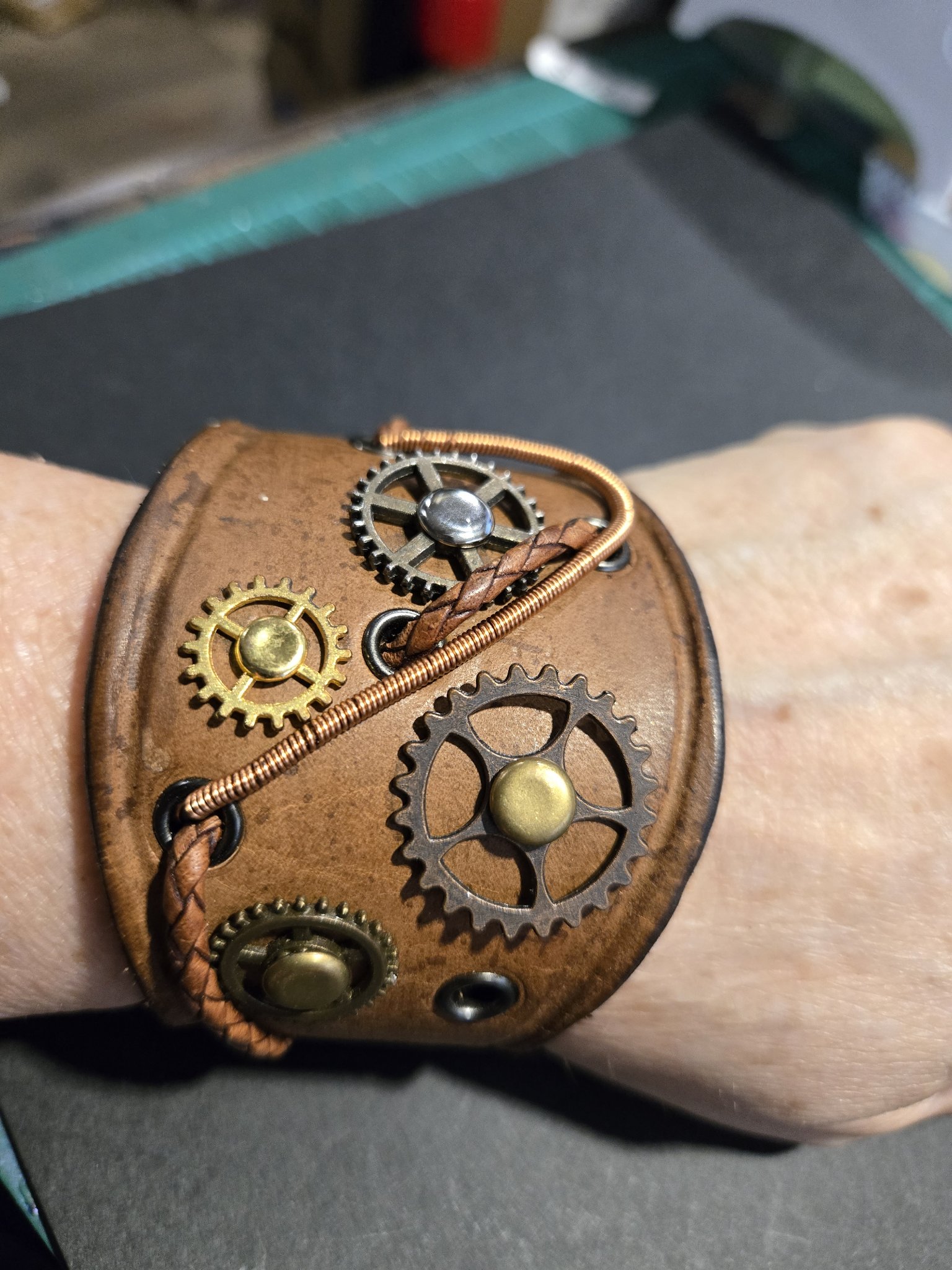 Stock 215 steampunk brown leather cuff with metal gears and copper-colored wire, shown on a wrist
