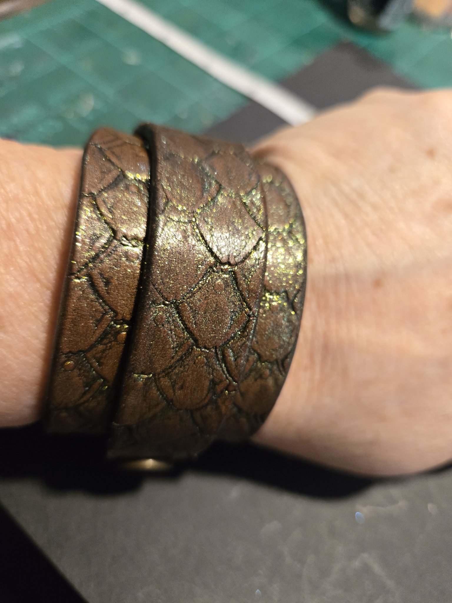Close-up of stock 223 on a wrist showing the gold and green shimmer across the dragon scales