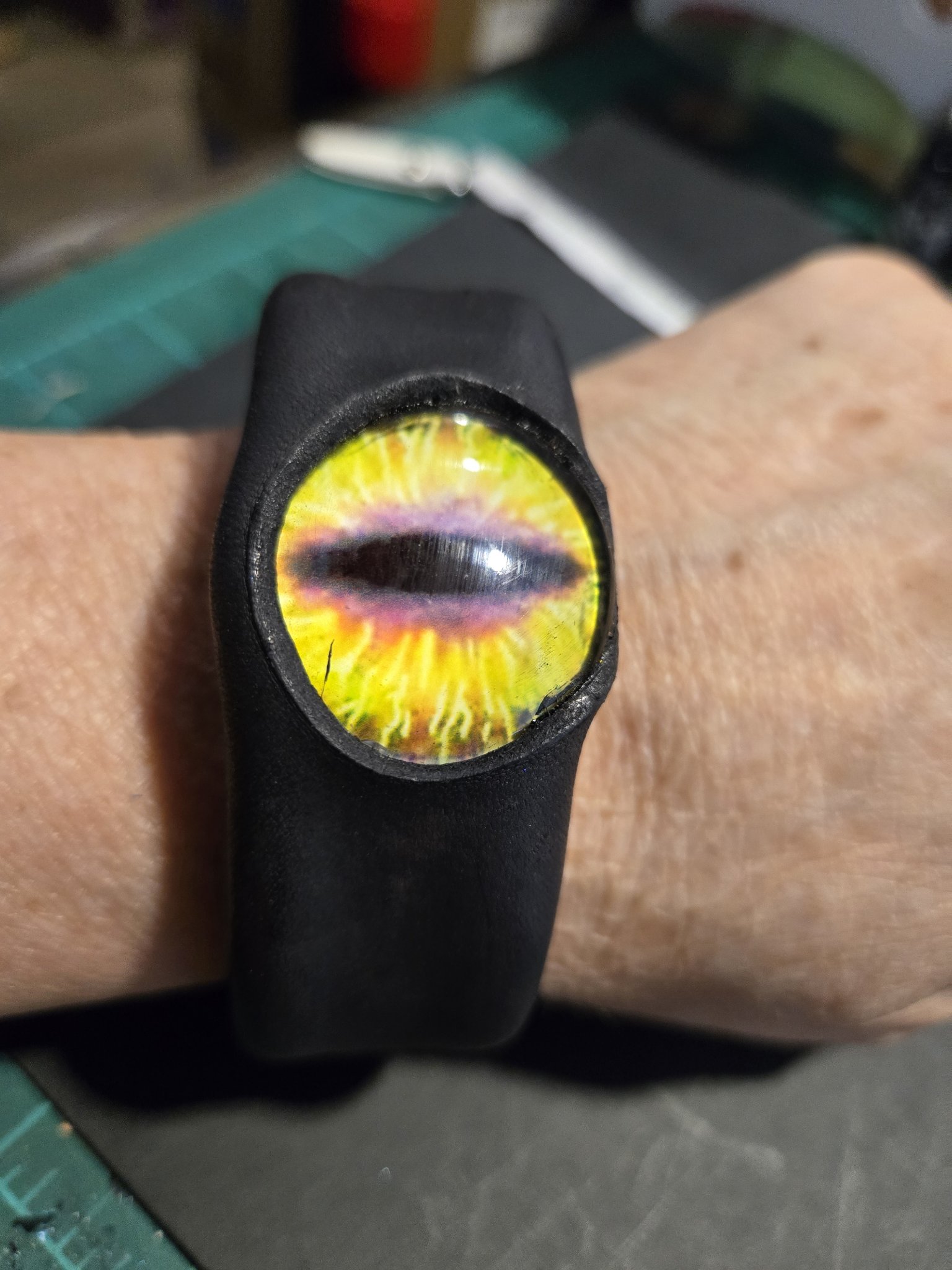 Stock 227 black leather cuff with a fiery yellow dragon eye, shown on a wrist