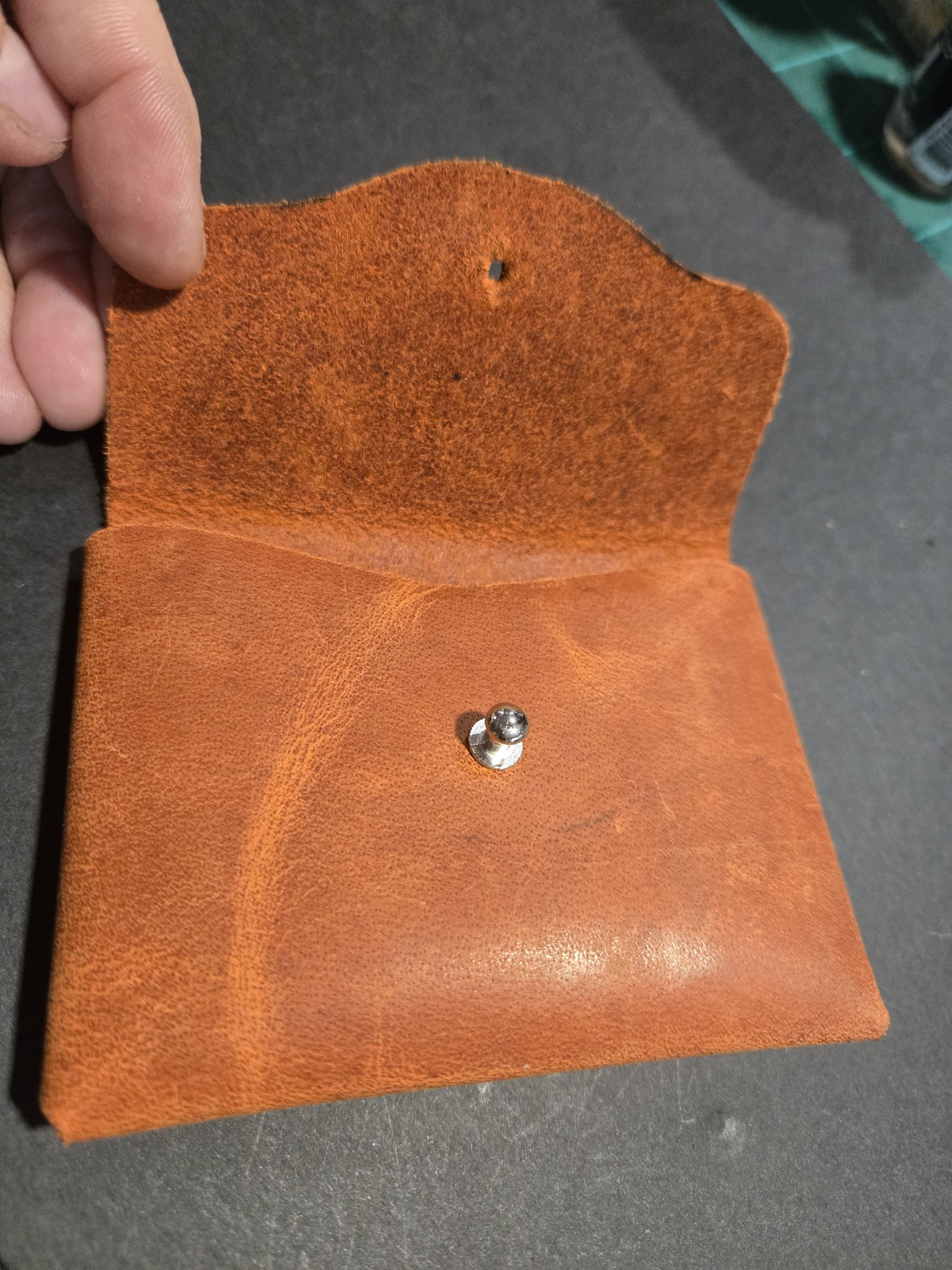 Stock 242 held open with the flap raised, showing the soft suede underside of the flap and the silver-tone stud closure